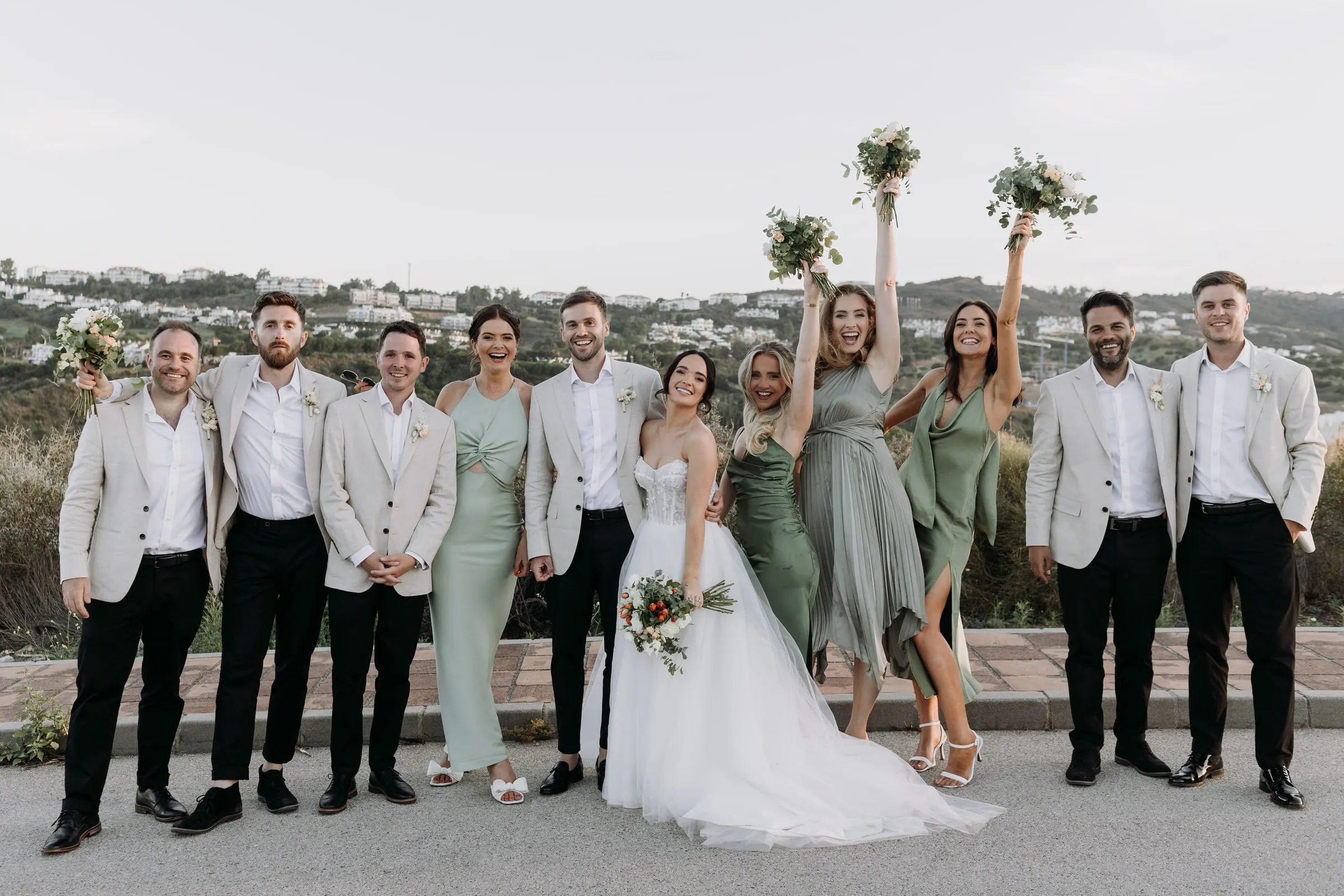 Bridesmaids raising their bouquets in the air beside the groomsmen, Mijas