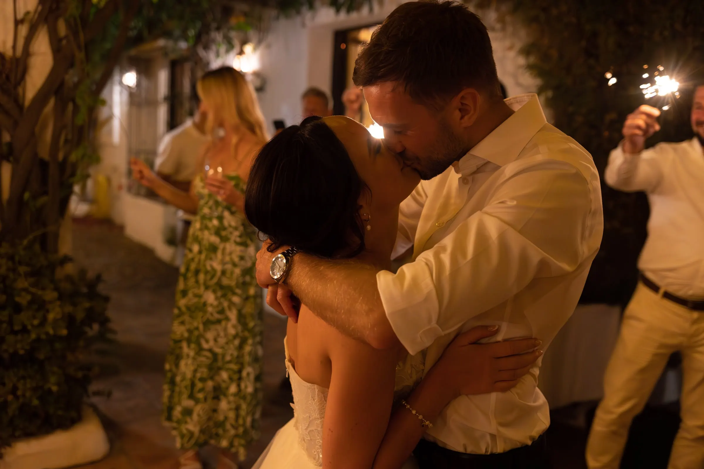 Bride and groom kissing as the sparklers burn around them, Hacienda San José