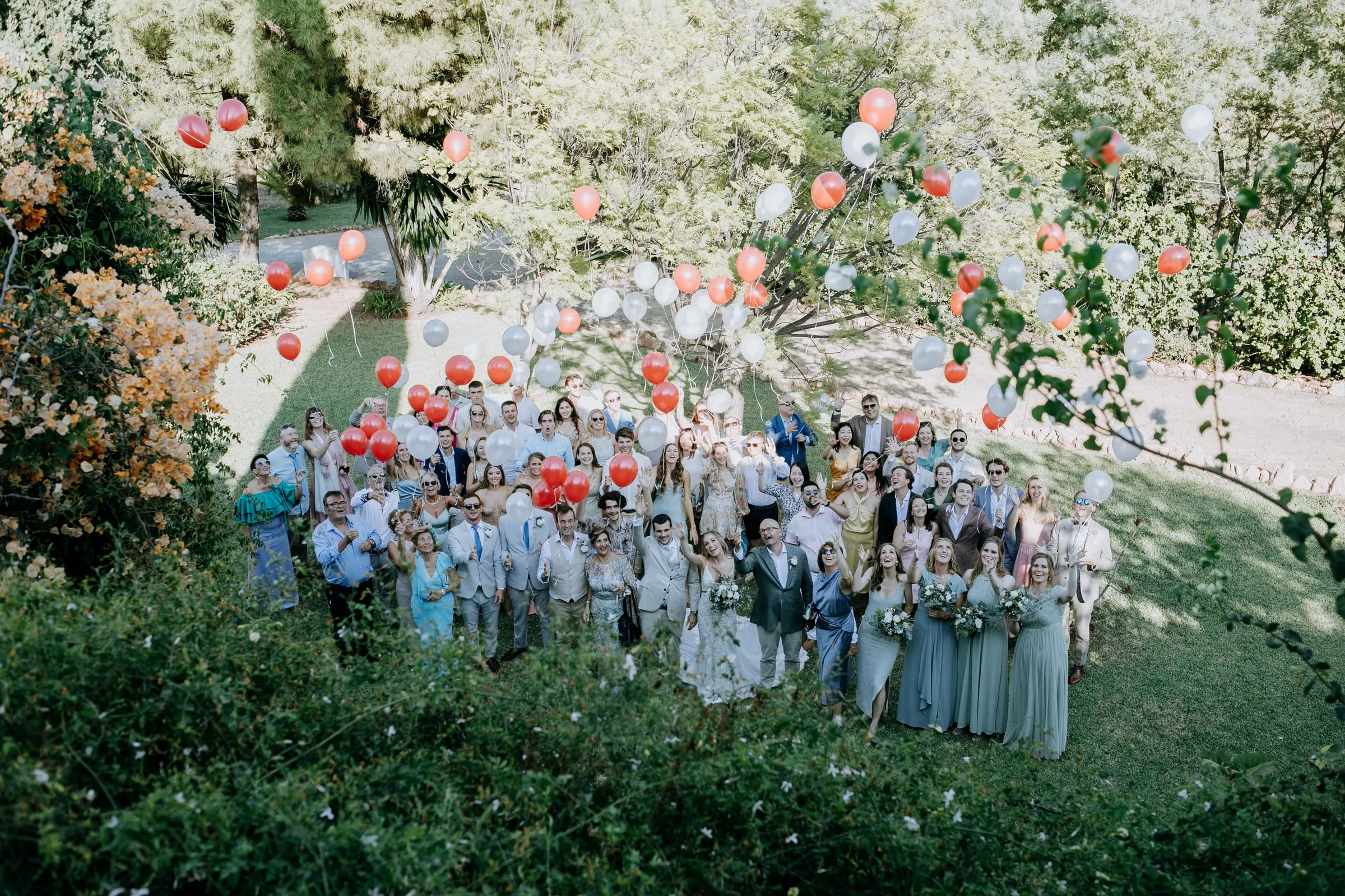 Group photo of all the guests on the lawn releasing red and white balloons, Hacienda San José, Mijas