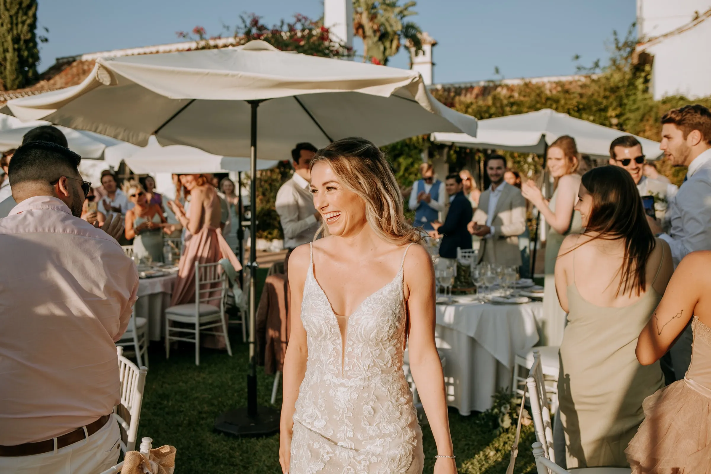 Bride smiling among guests under white parasols at the garden drinks reception, Hacienda San José, Mijas