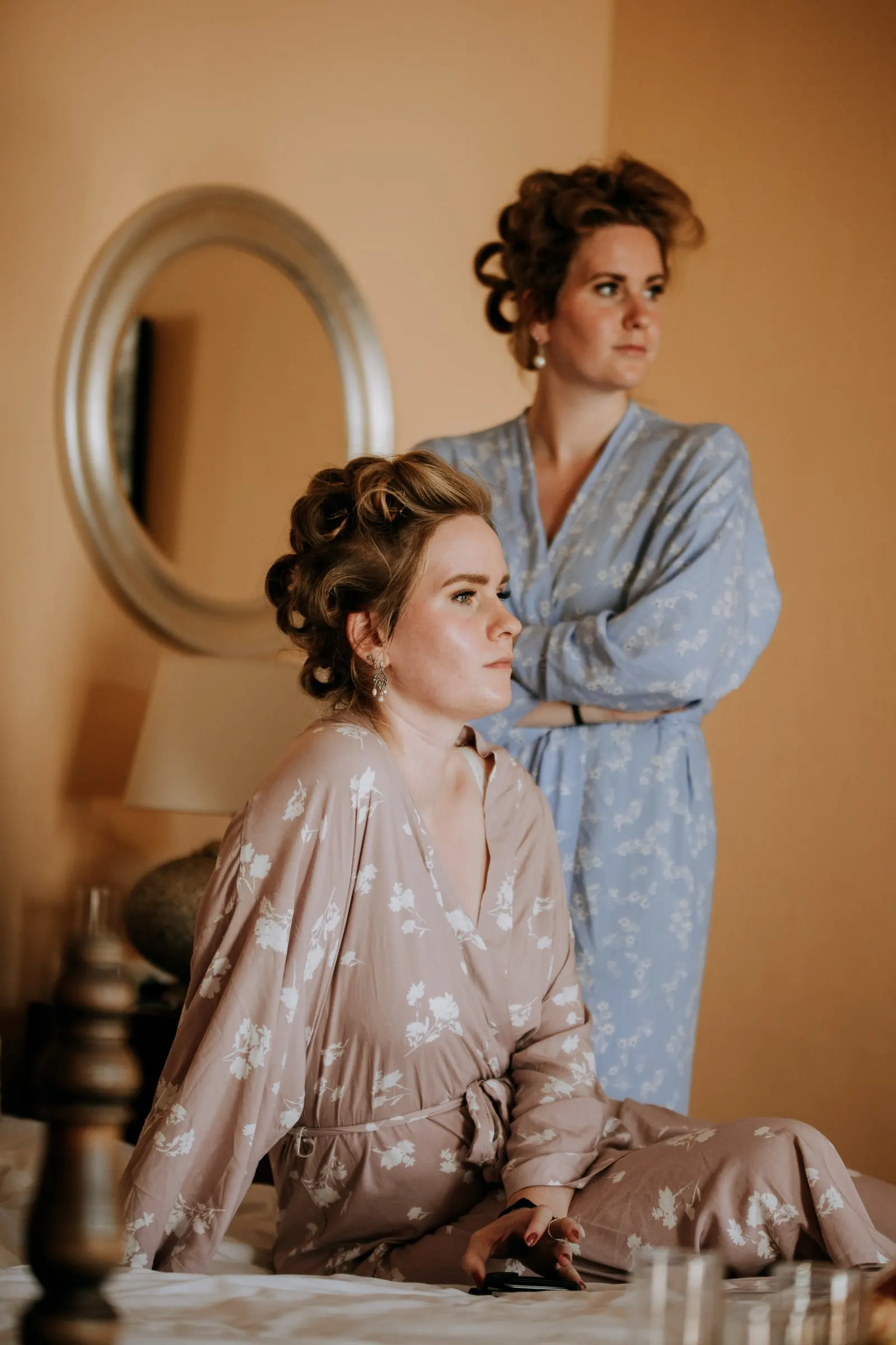 Two women in floral robes and hair rollers getting ready by a round mirror, Hacienda San José, Mijas