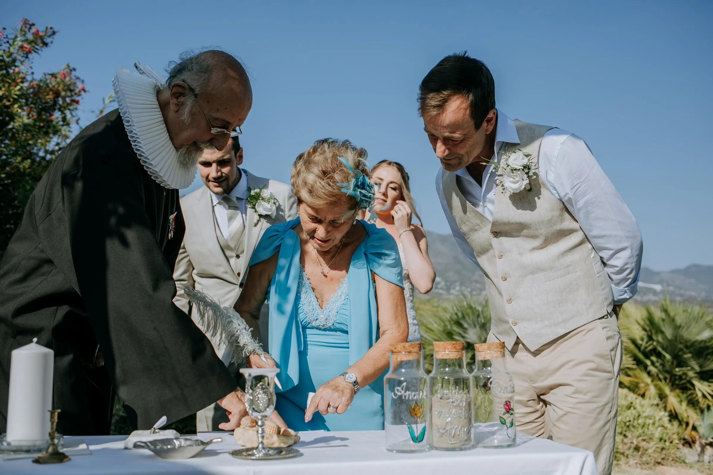 Parents and the couple pour coloured sand into a jar at the ceremony table, Hacienda San José, Mijas