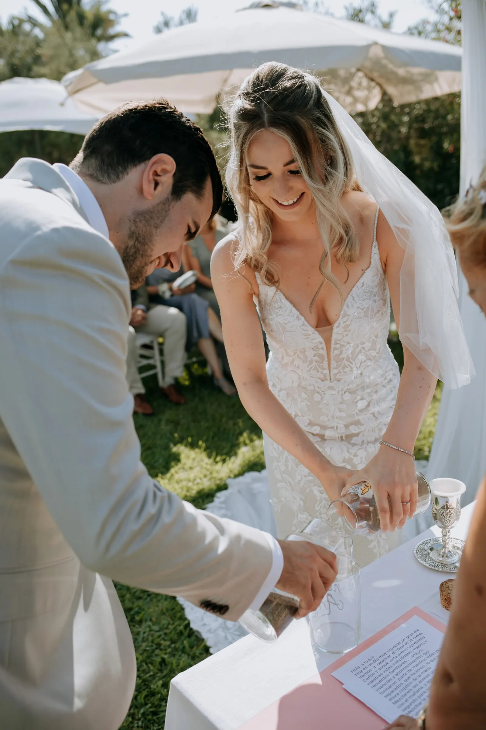 Bride and groom laughing as they add sand to the jar during the ceremony, Hacienda San José, Mijas