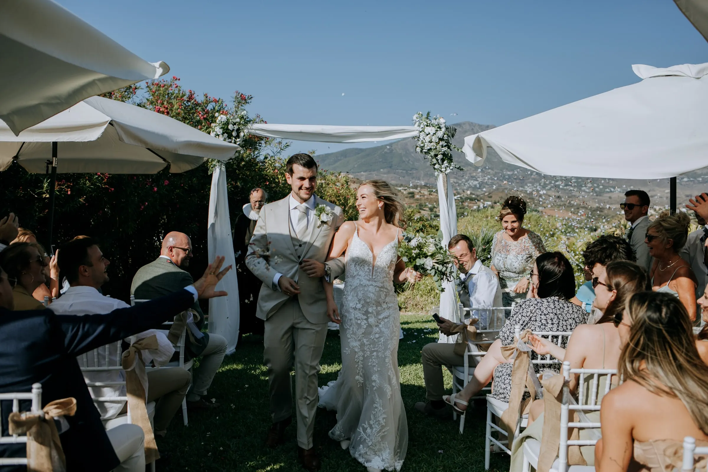 Bride and groom walking up the aisle as guests reach out to congratulate them, Hacienda San José, Mijas