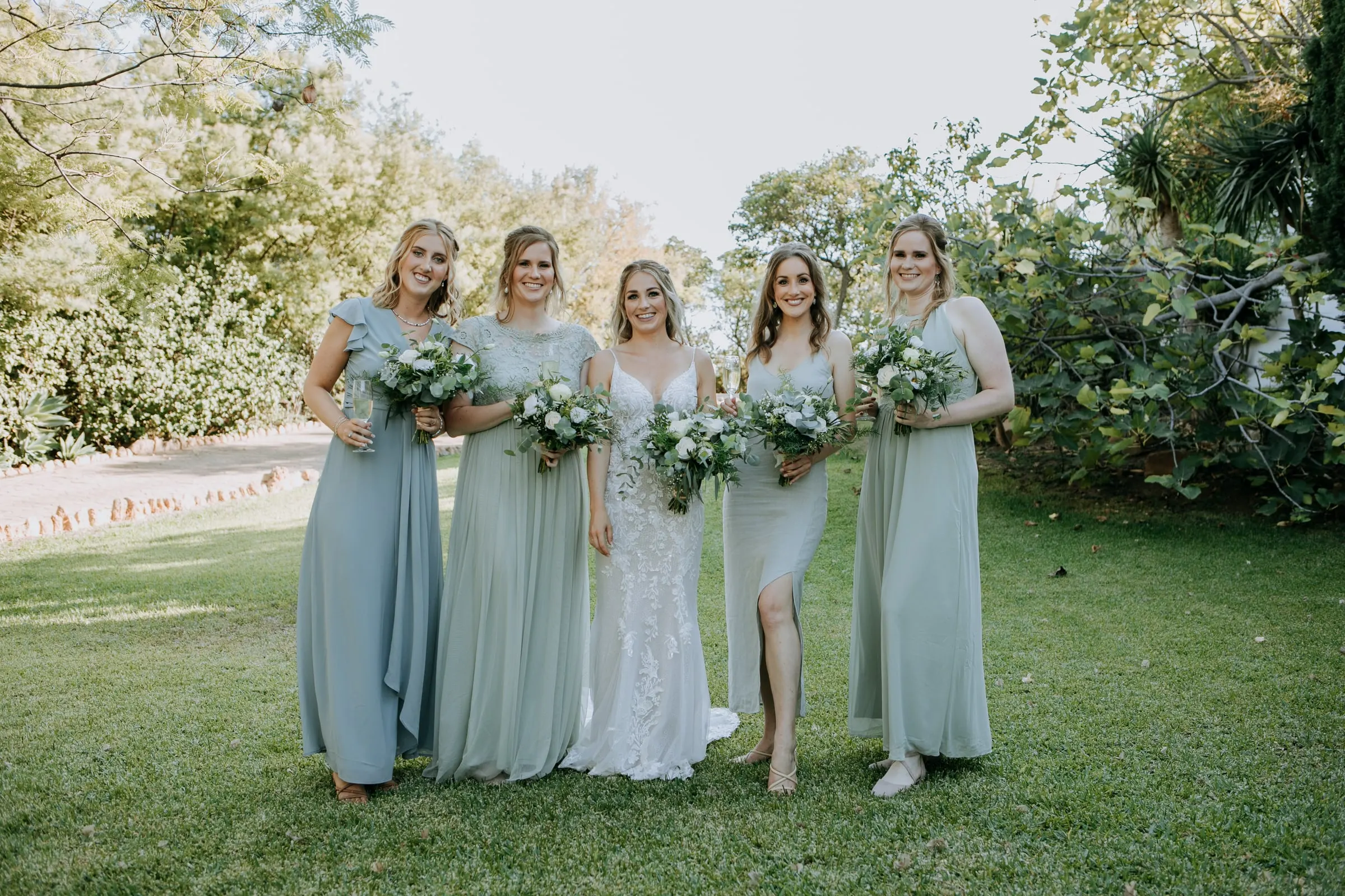 Bride with her four bridesmaids in pale green and blue walking across the lawn, Hacienda San José, Mijas