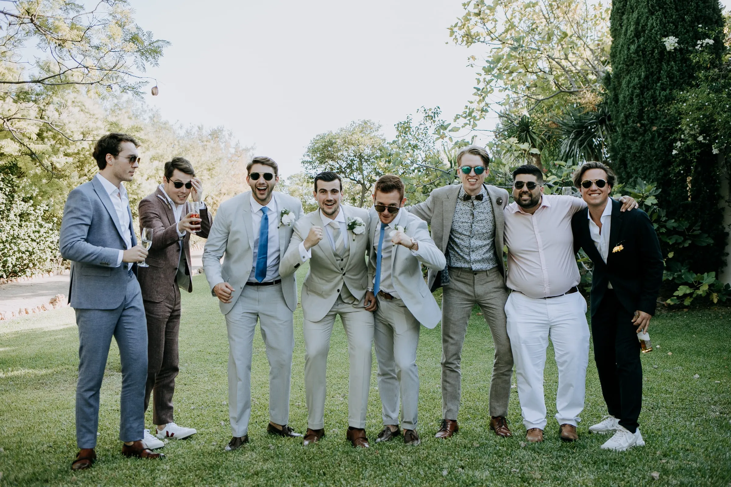 Groom and his friends in suits and sunglasses striking a pose on the lawn, Hacienda San José, Mijas