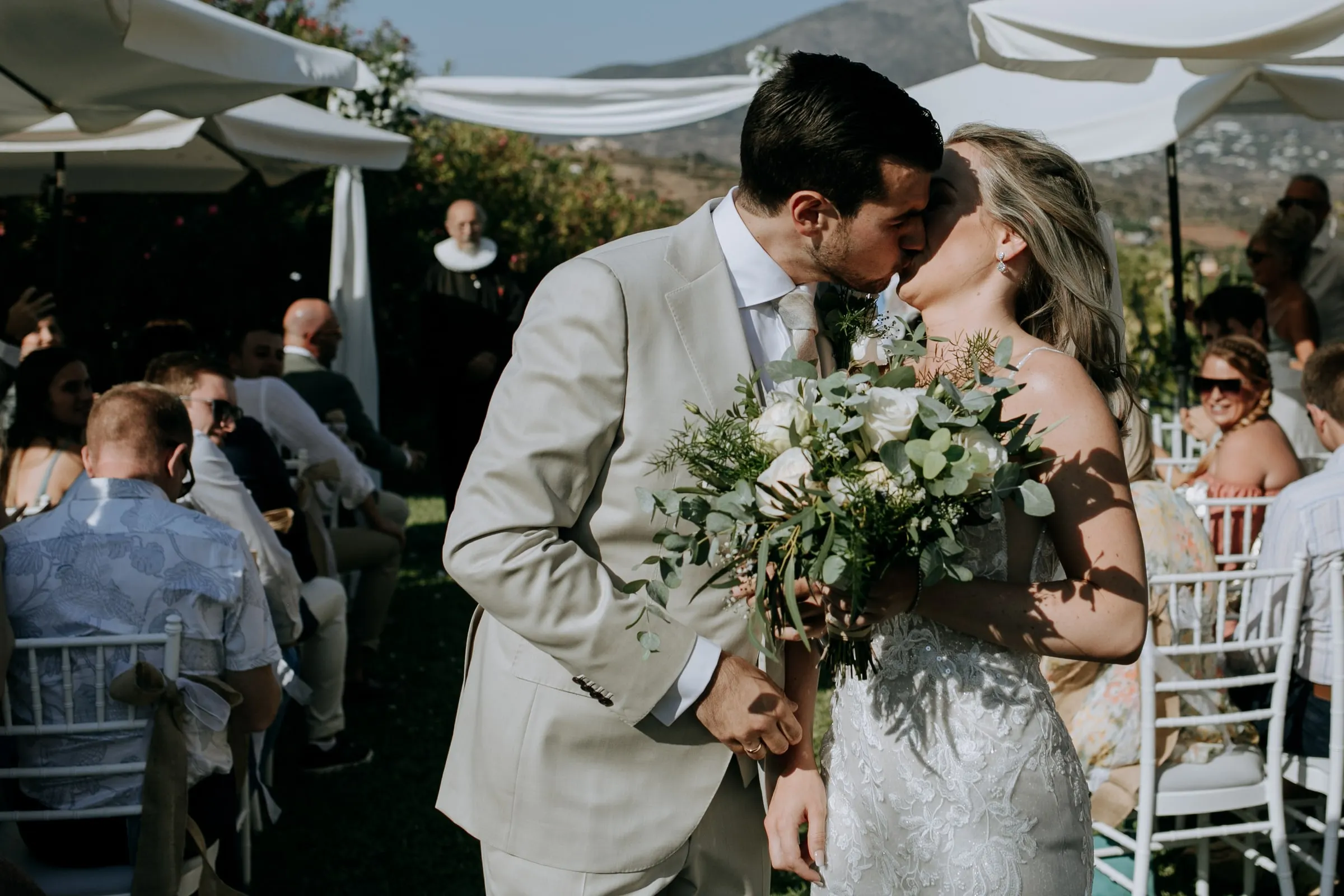 Groom kissing the bride as they walk back down the aisle between the guests, Hacienda San José, Mijas