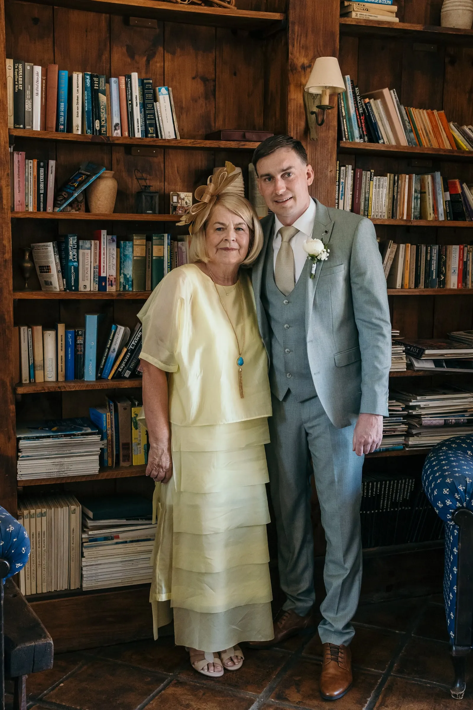 Groom with a guest in a pale yellow dress among bookshelves, Mijas