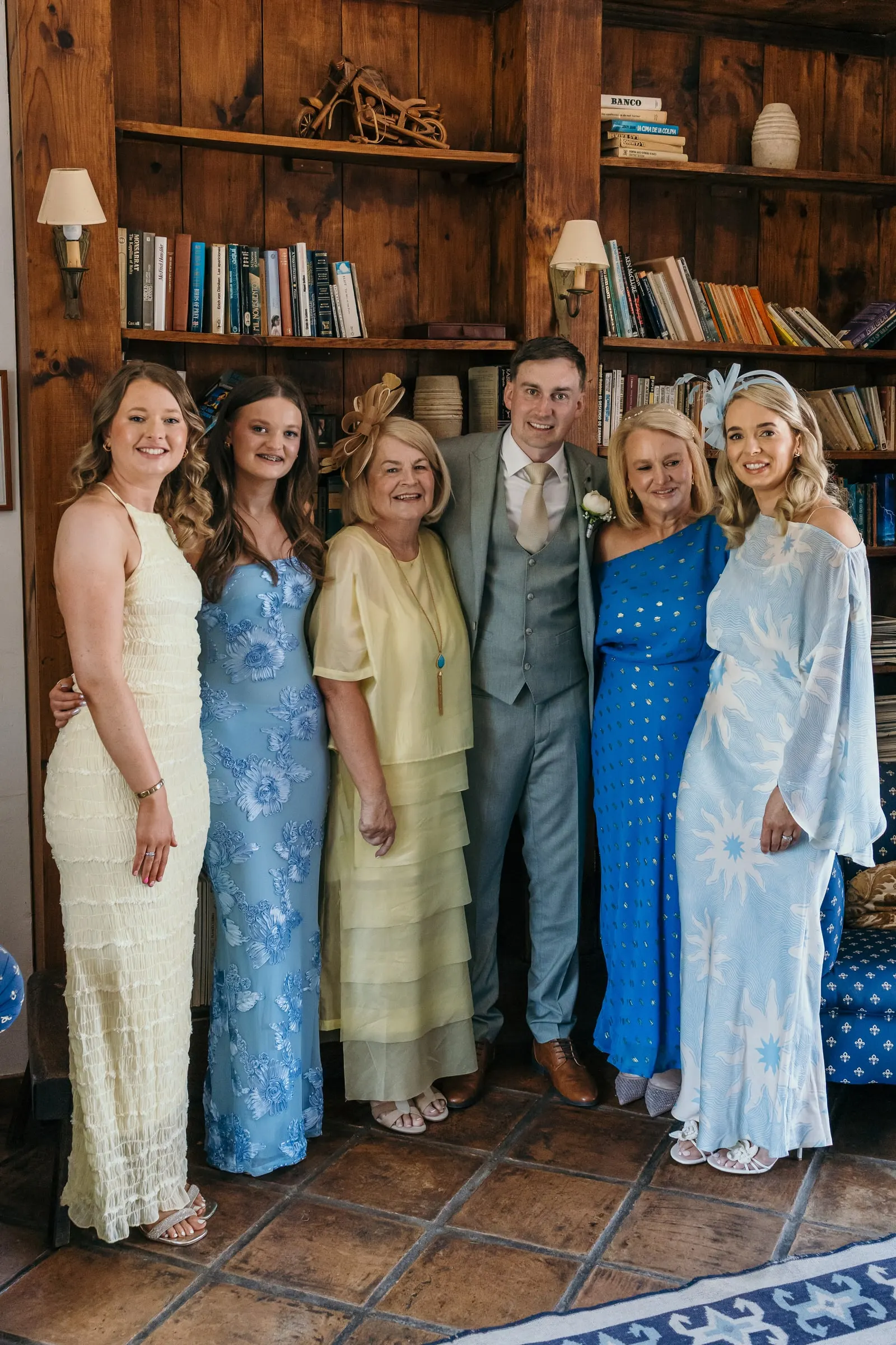 Groom with five guests in summer dresses in the library at Hacienda San José