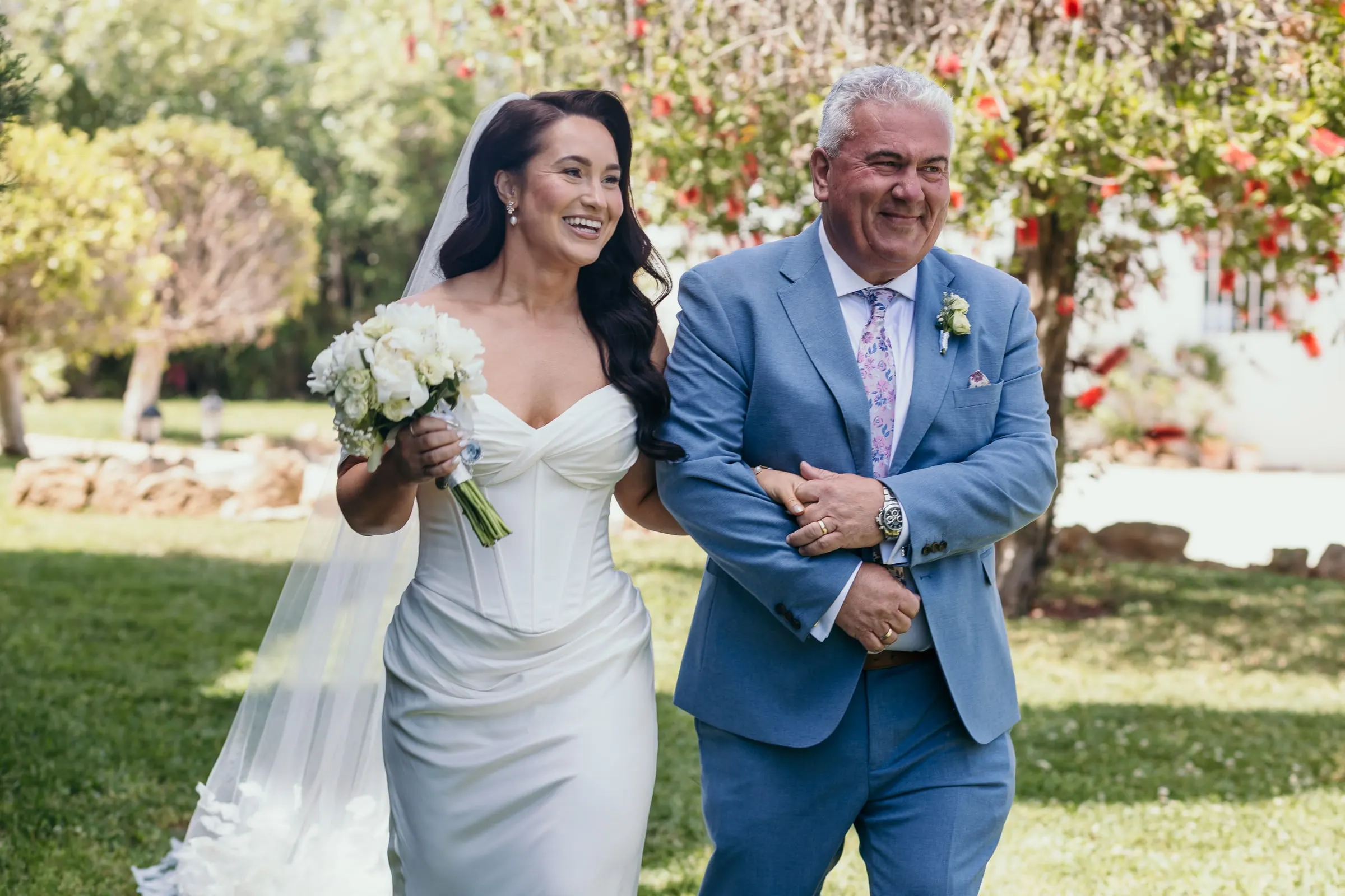 Bride crossing the lawn on the arm of a man in a blue suit, Hacienda San José