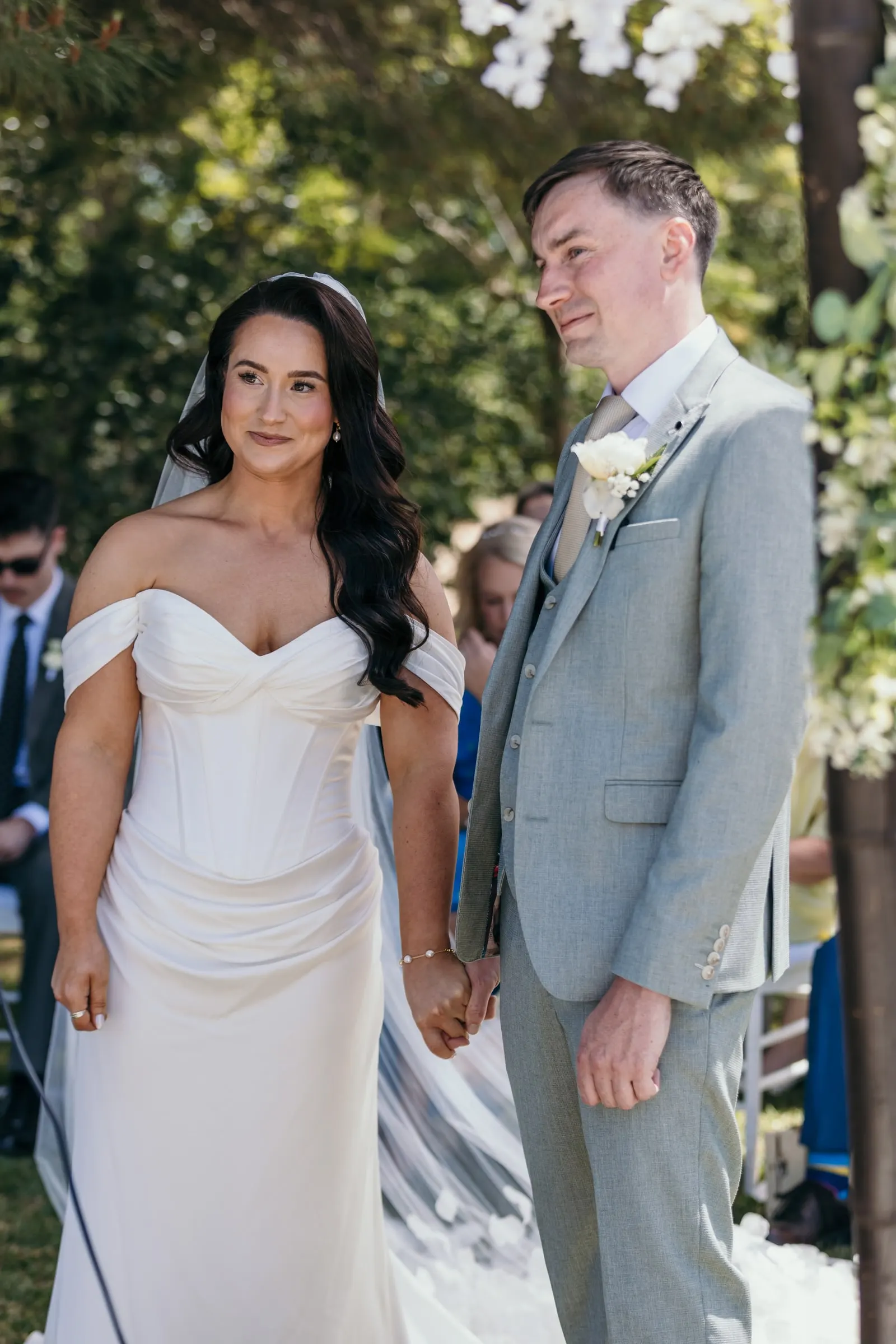 Bride and groom holding hands in front of the guests at the garden ceremony