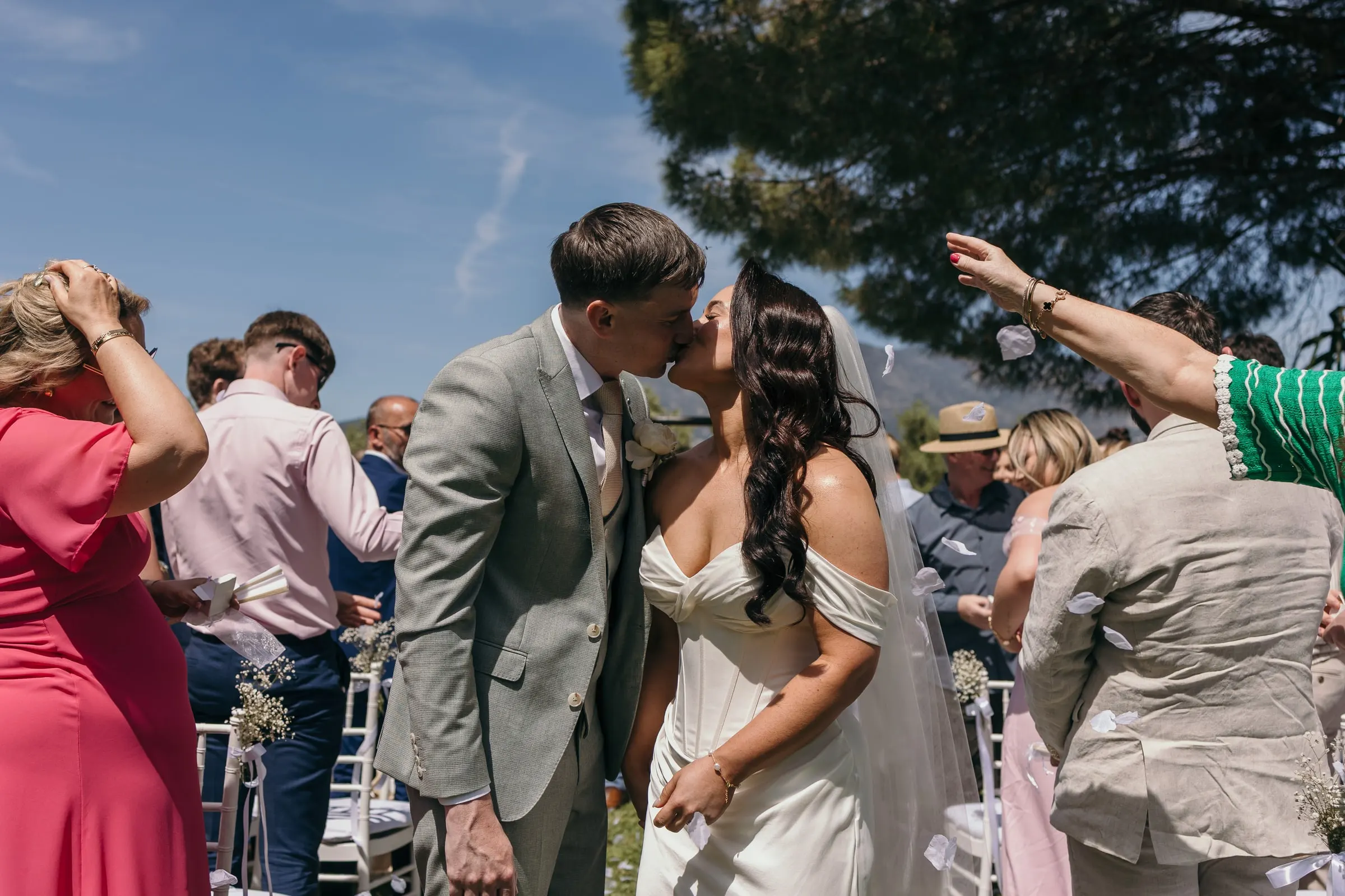 Newlyweds kissing in the aisle as guests throw petals over them, Mijas