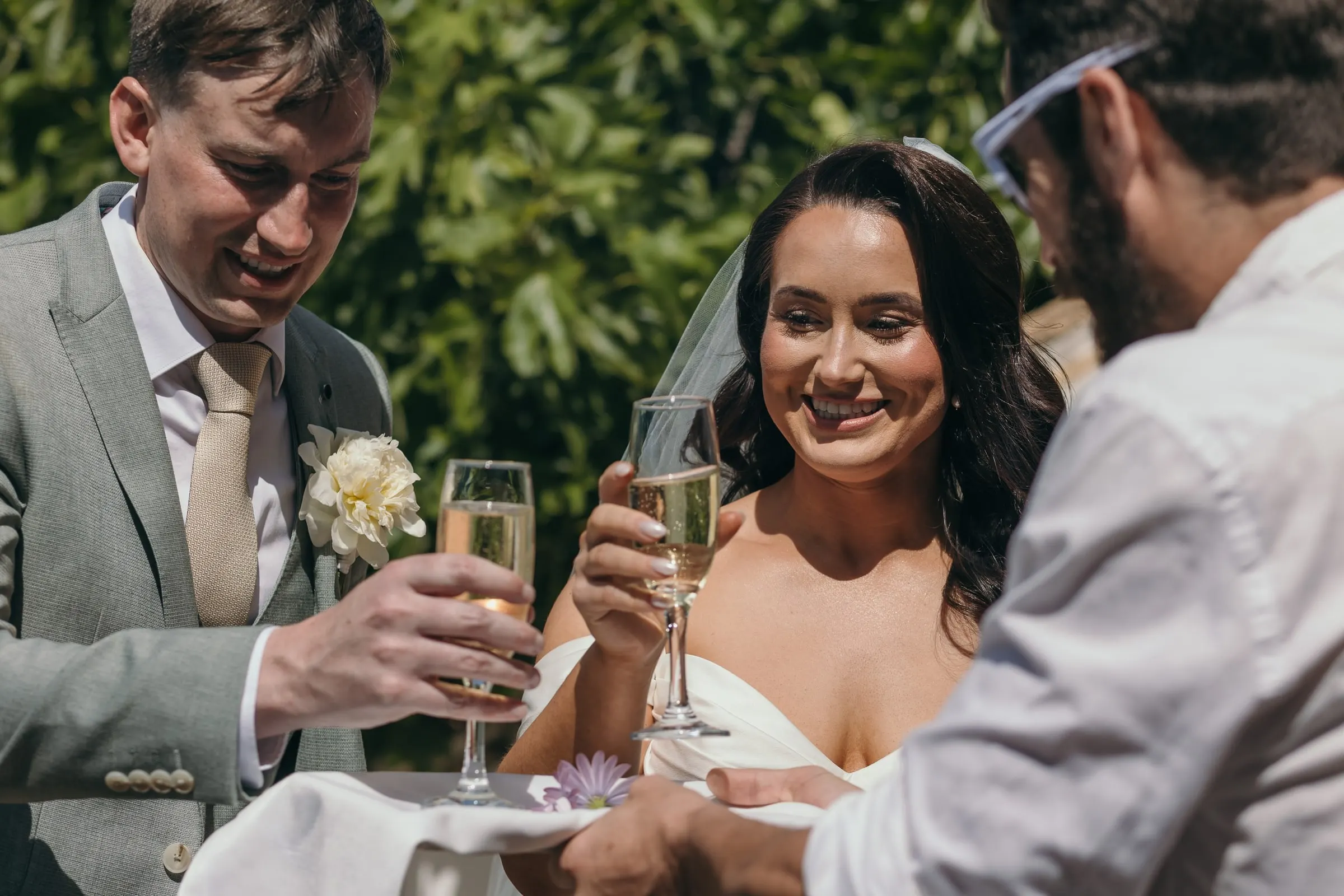 Bride and groom toasting with a friend at the drinks reception