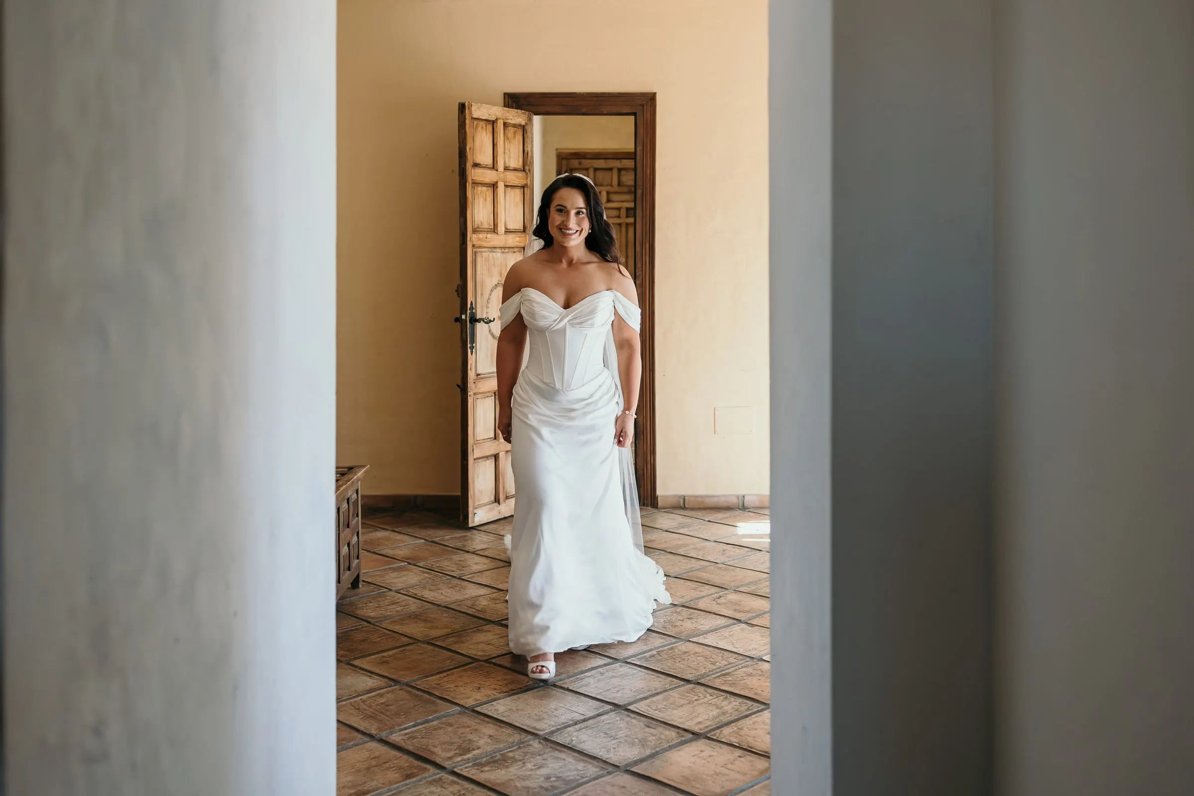 Bride walking through a tiled room between white columns