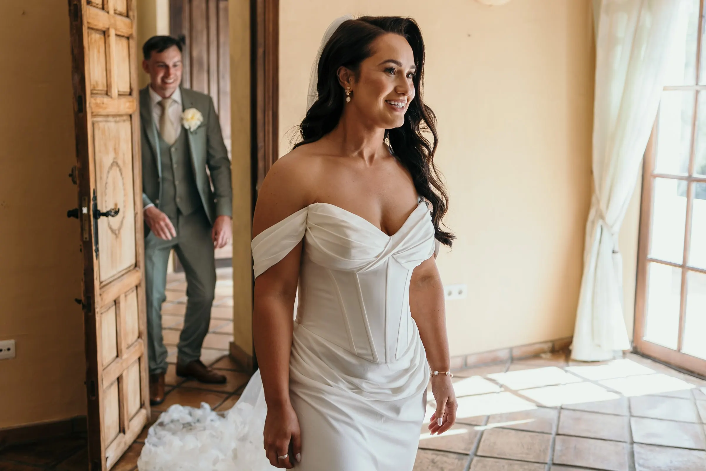 Groom watching the bride from a wooden doorway