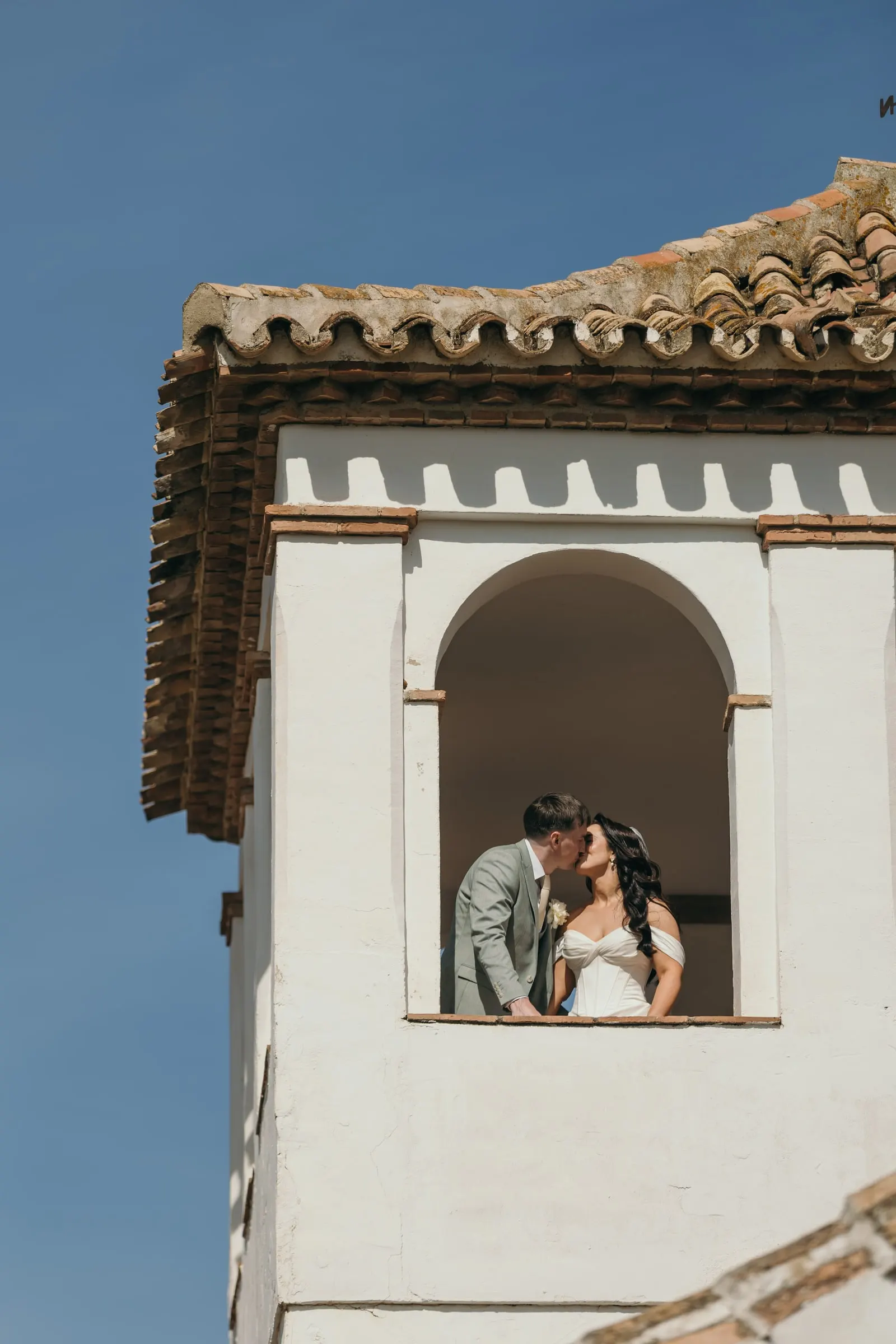 Couple kissing in the arched window of the white tower, Hacienda San José