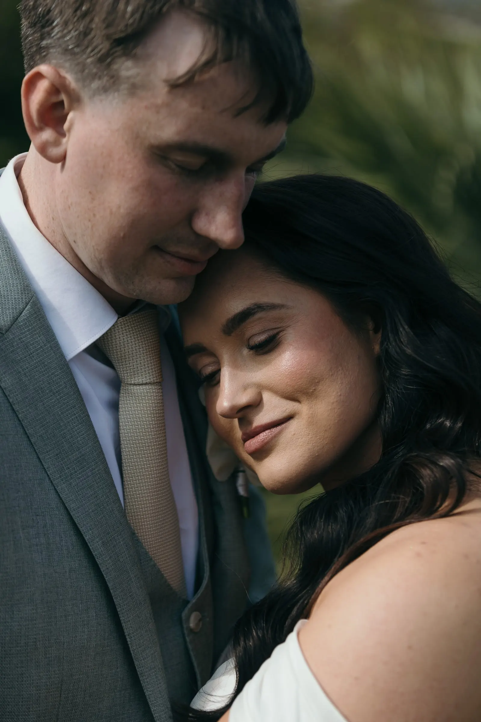 Close portrait of the bride resting her head on the groom's chest