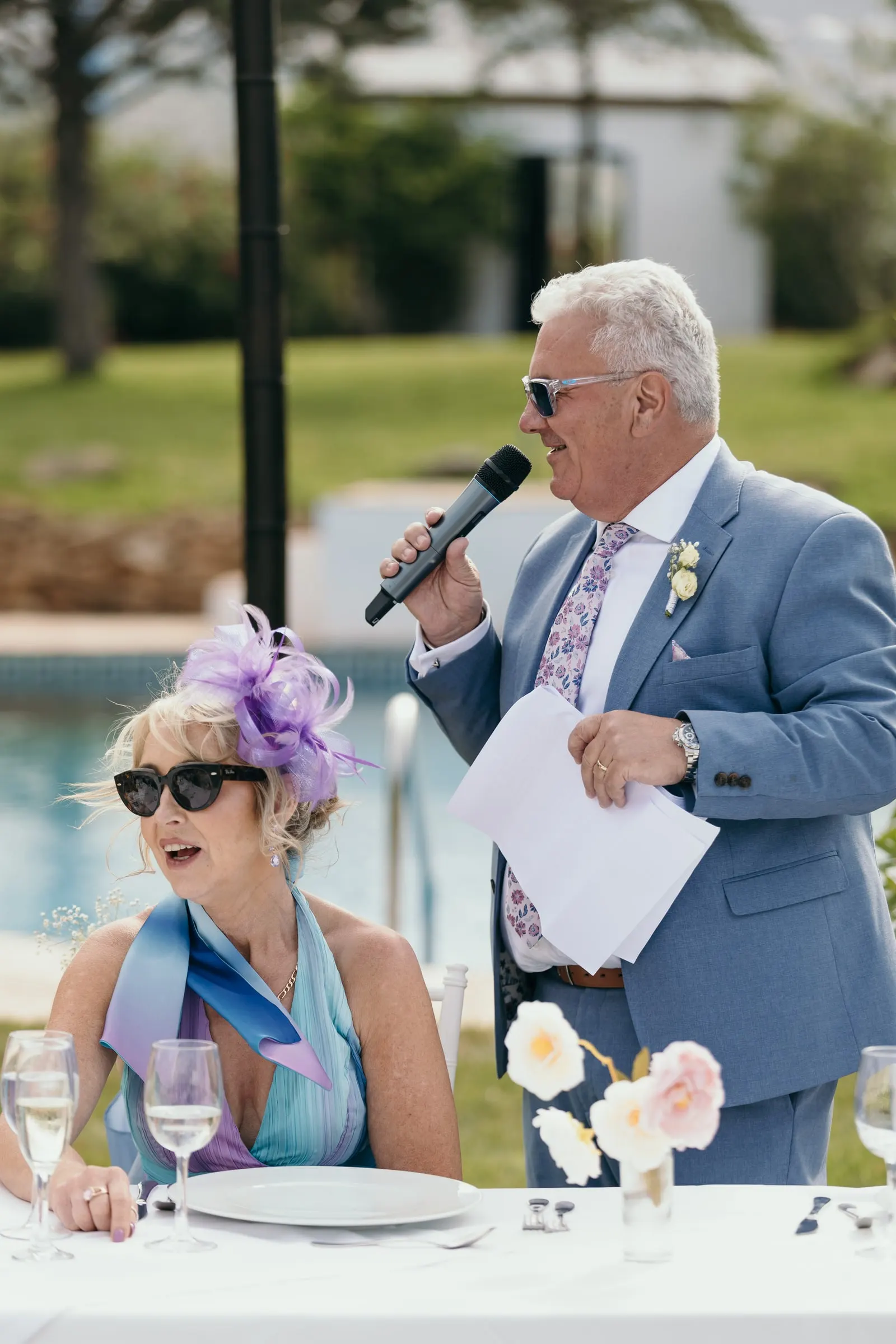 Man in a blue suit reading his speech by the pool