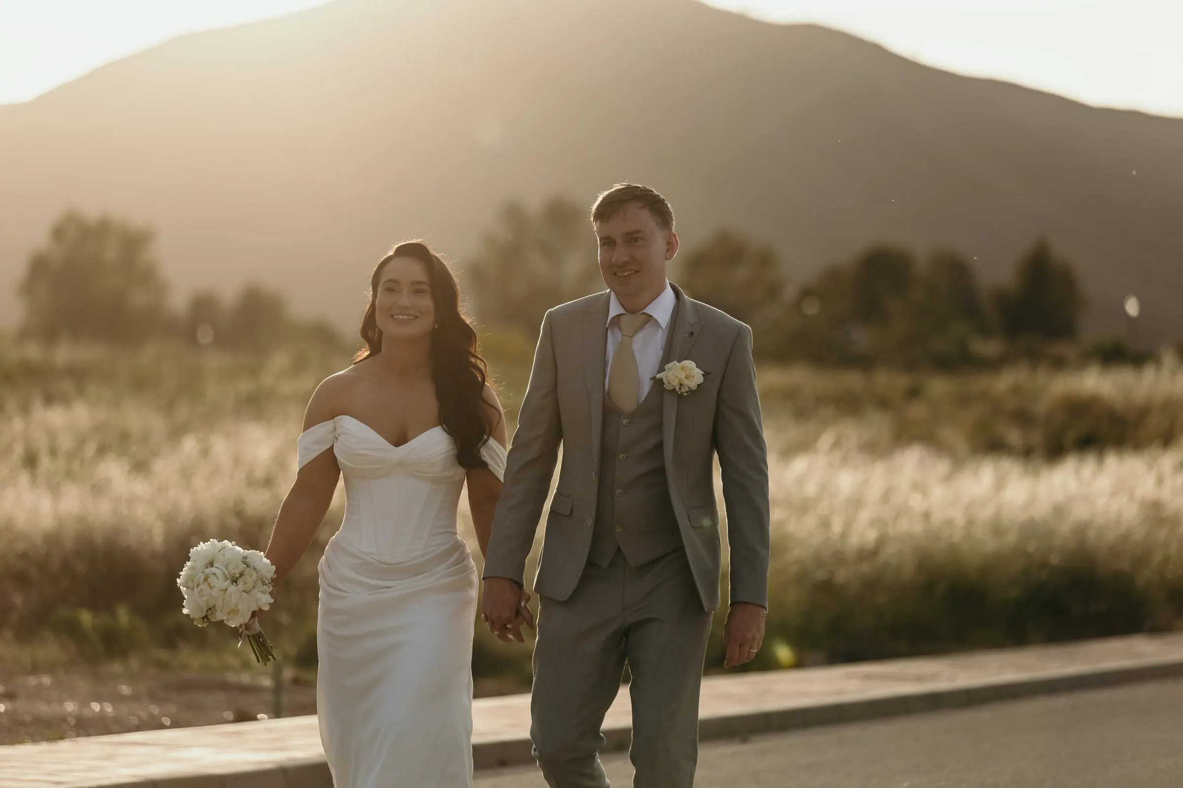 Newlyweds walking along a quiet road in the evening light
