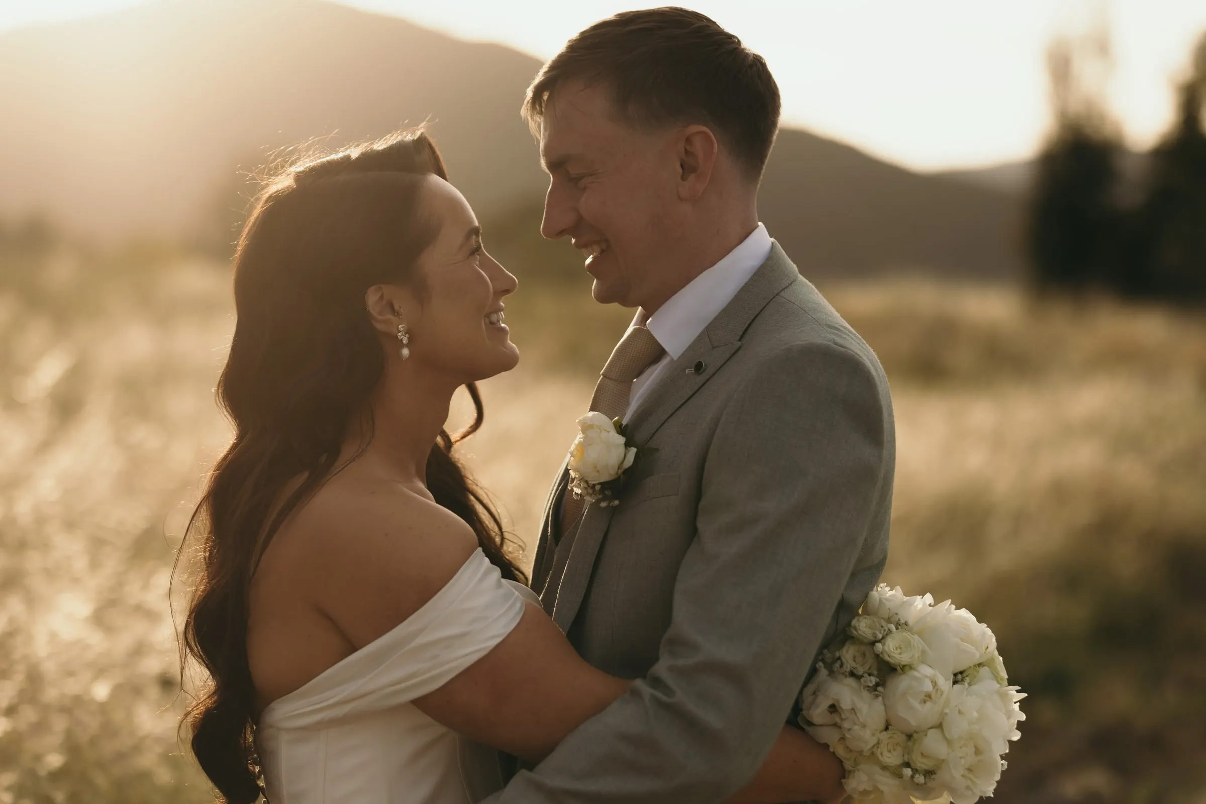 Bride and groom face to face in the long grass at golden hour, Mijas
