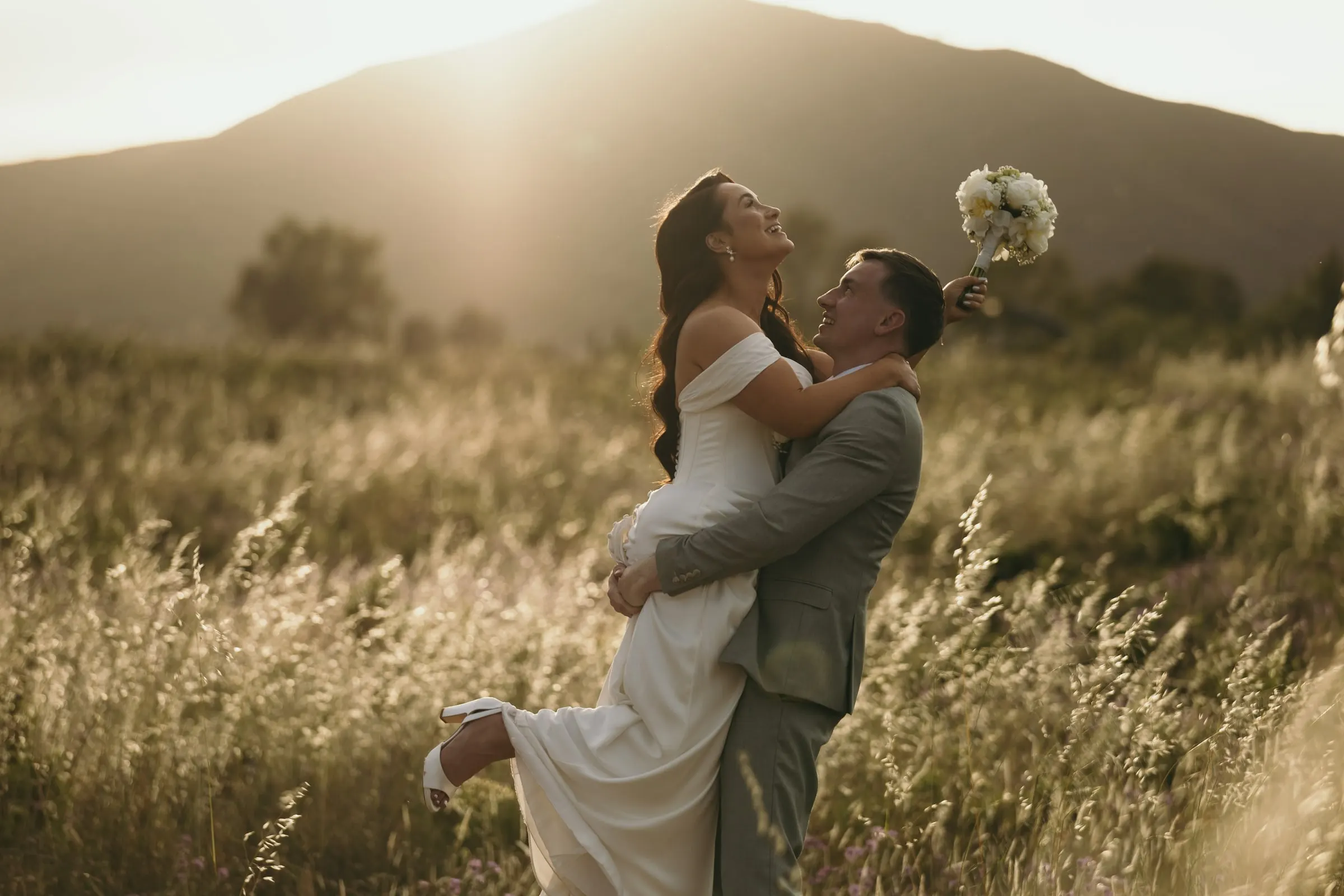 Groom lifting the bride in a meadow at sunset, the Sierra de Mijas behind