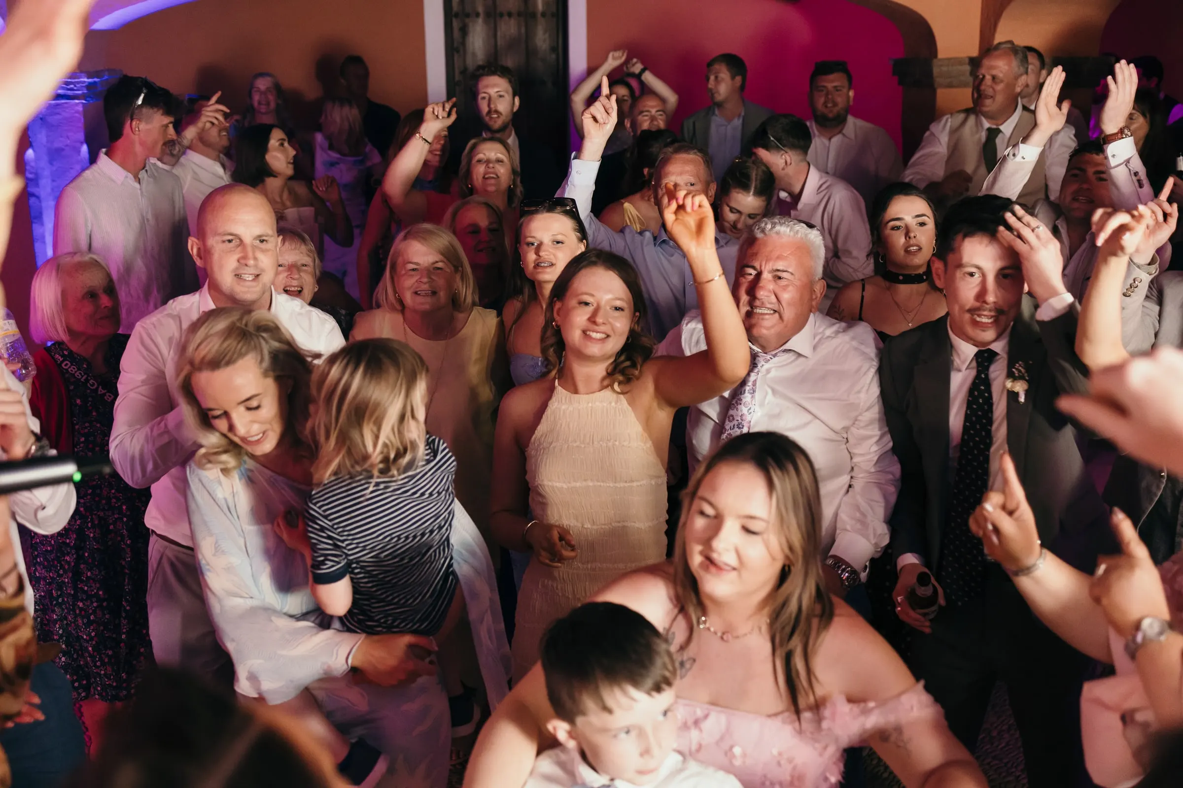 Guests singing with their arms up on the packed dance floor