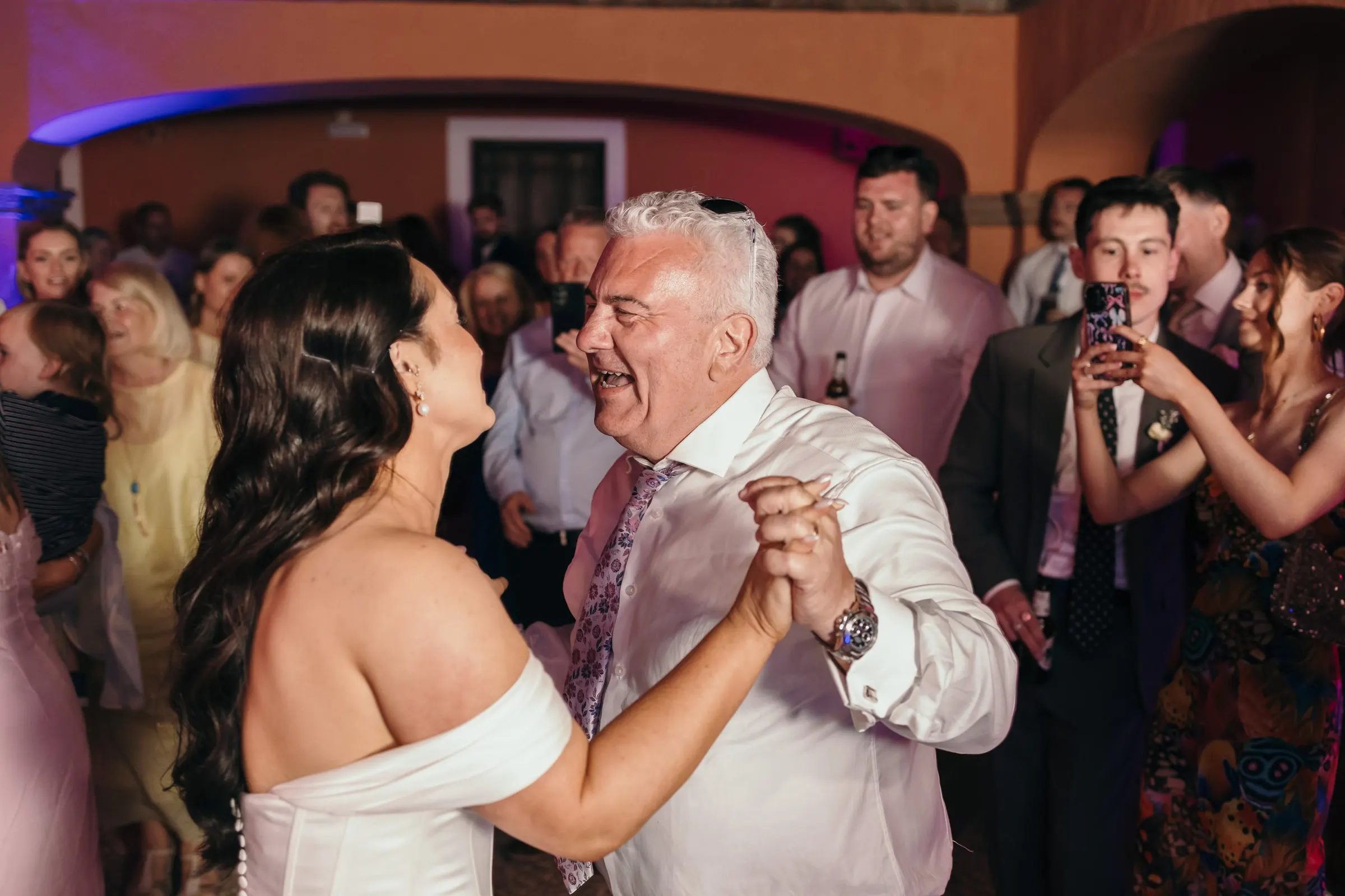 Bride dancing with a man in a white shirt in the courtyard