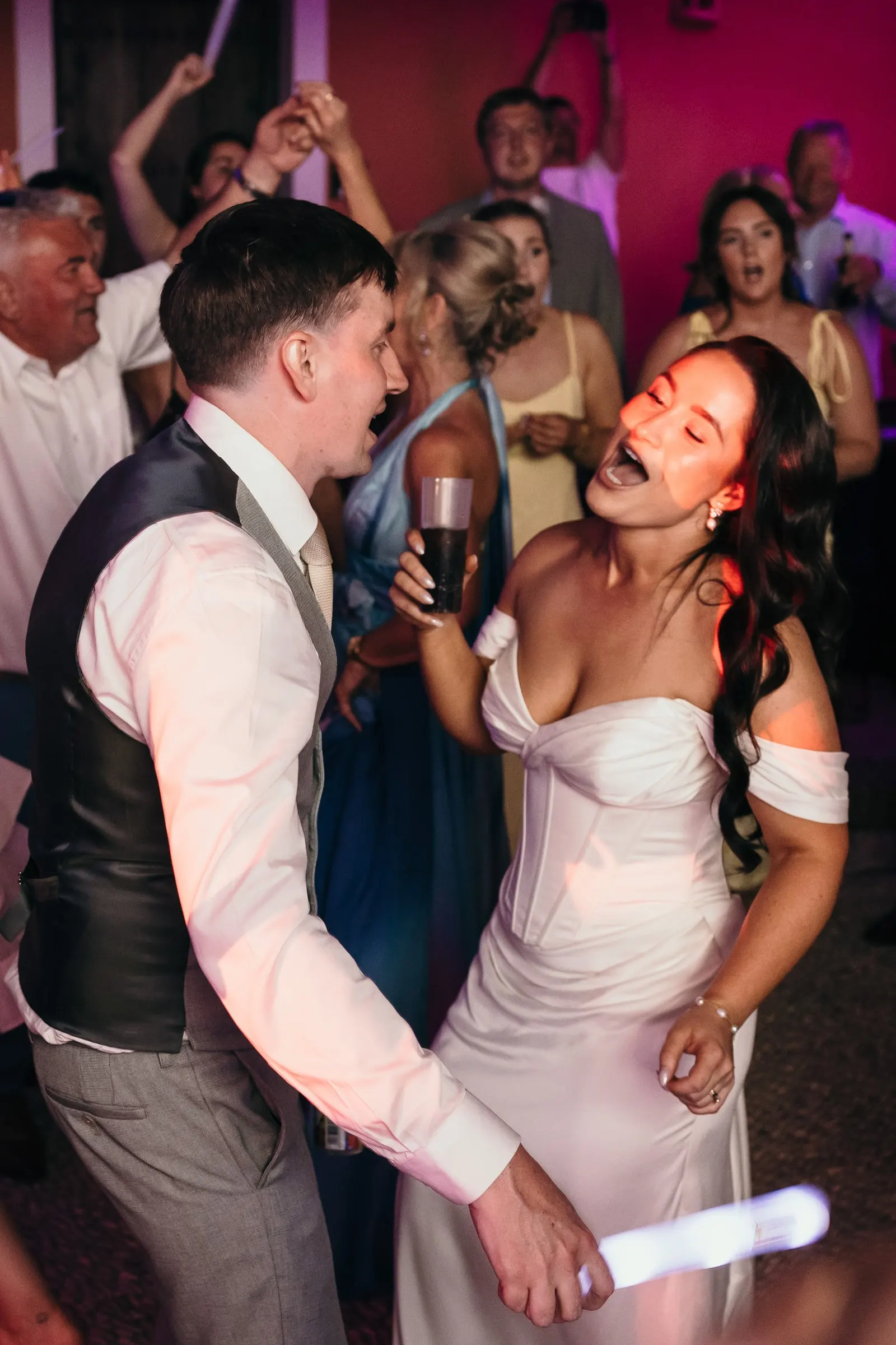 Bride and groom singing and dancing with glow sticks