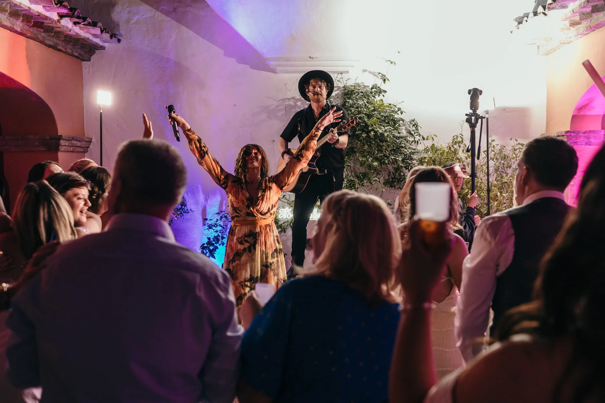 Band singer with arms open to the dancing guests in the courtyard, Mijas