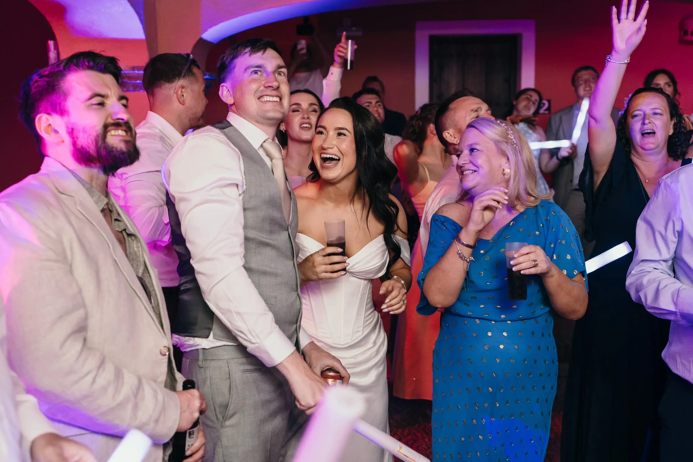 Bride, groom and friends singing together on the dance floor
