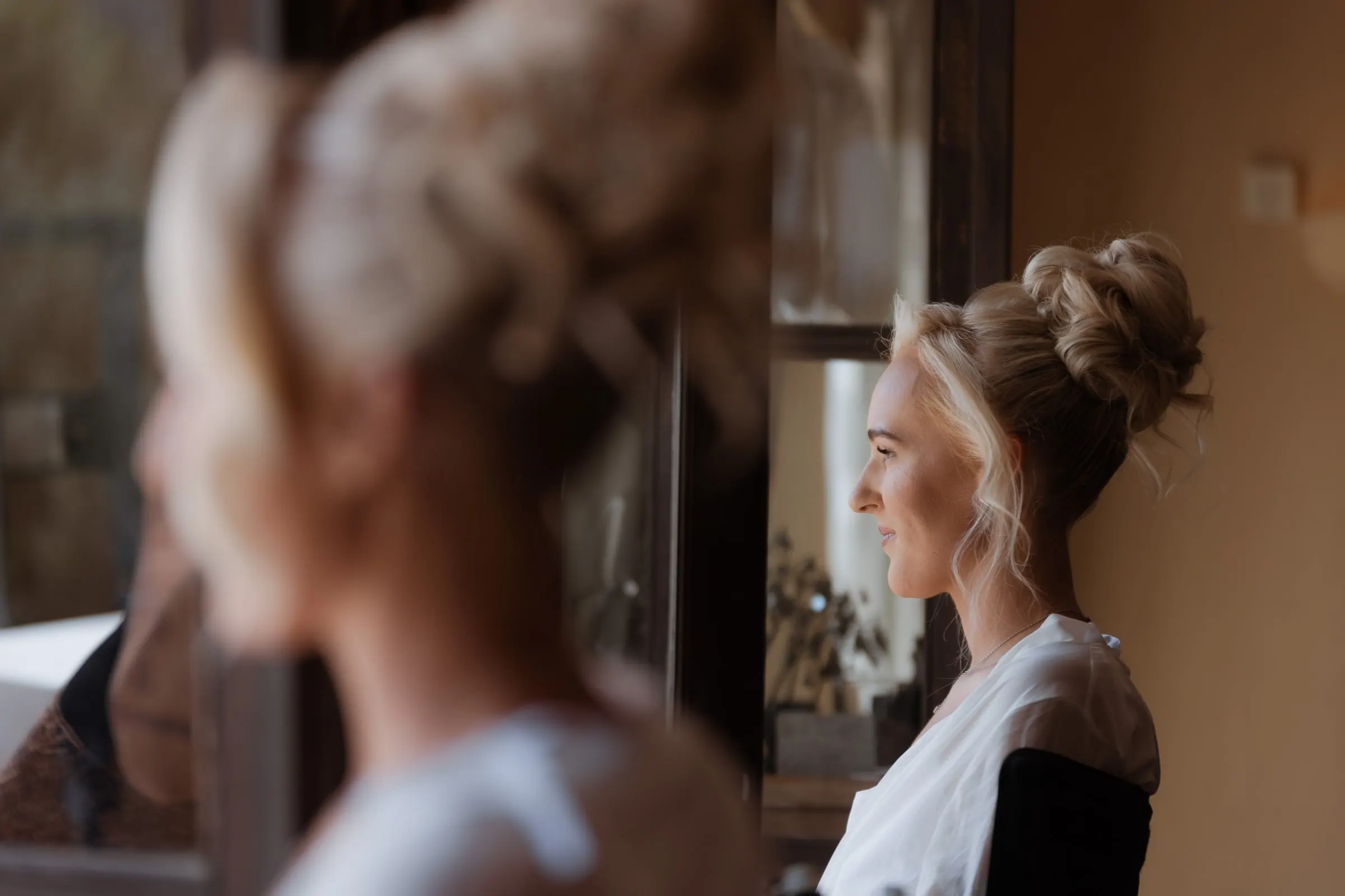 Bride with her hair up looking out of the window while getting ready in Mijas