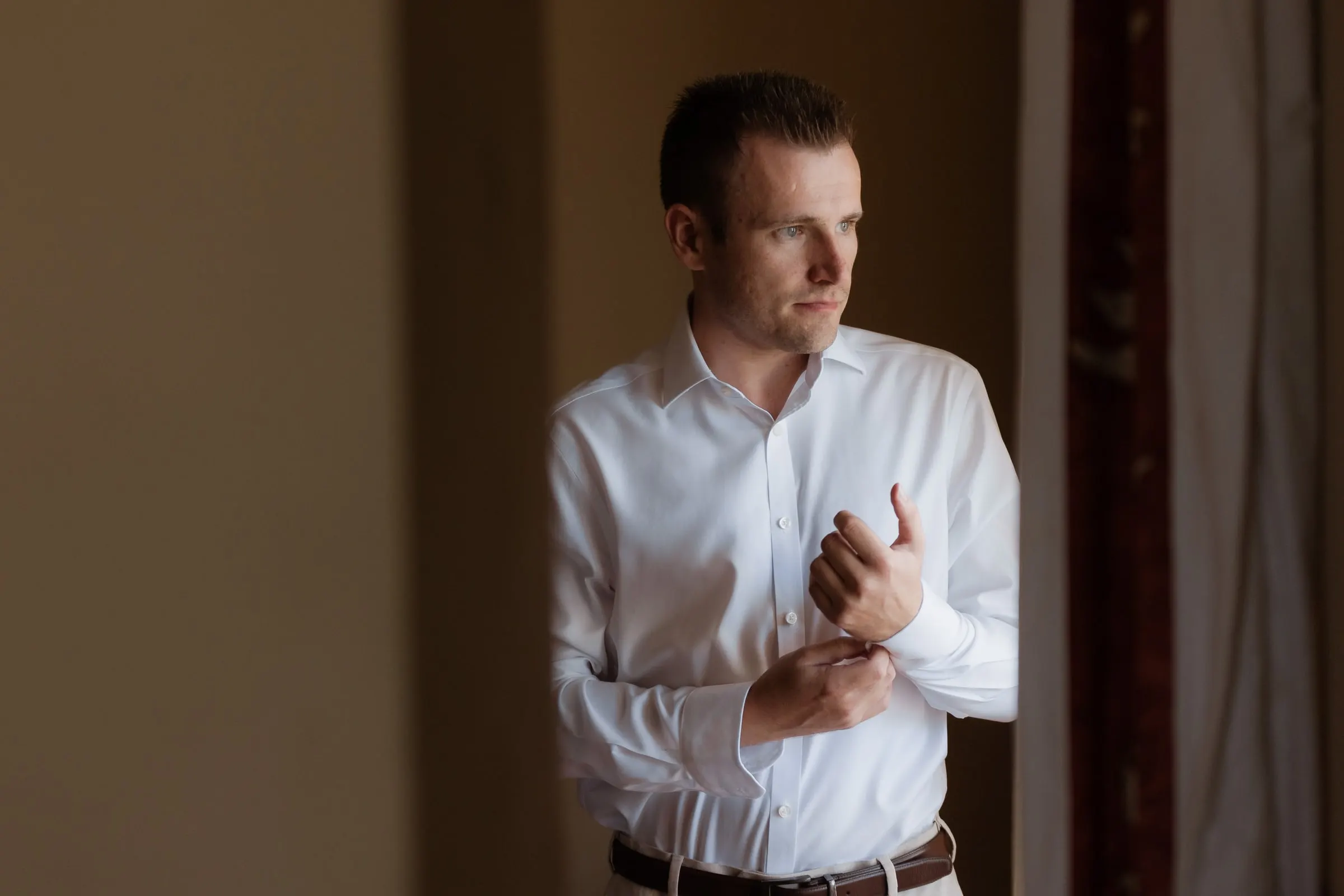 Groom fastening his shirt cuffs before the wedding at Hacienda San José