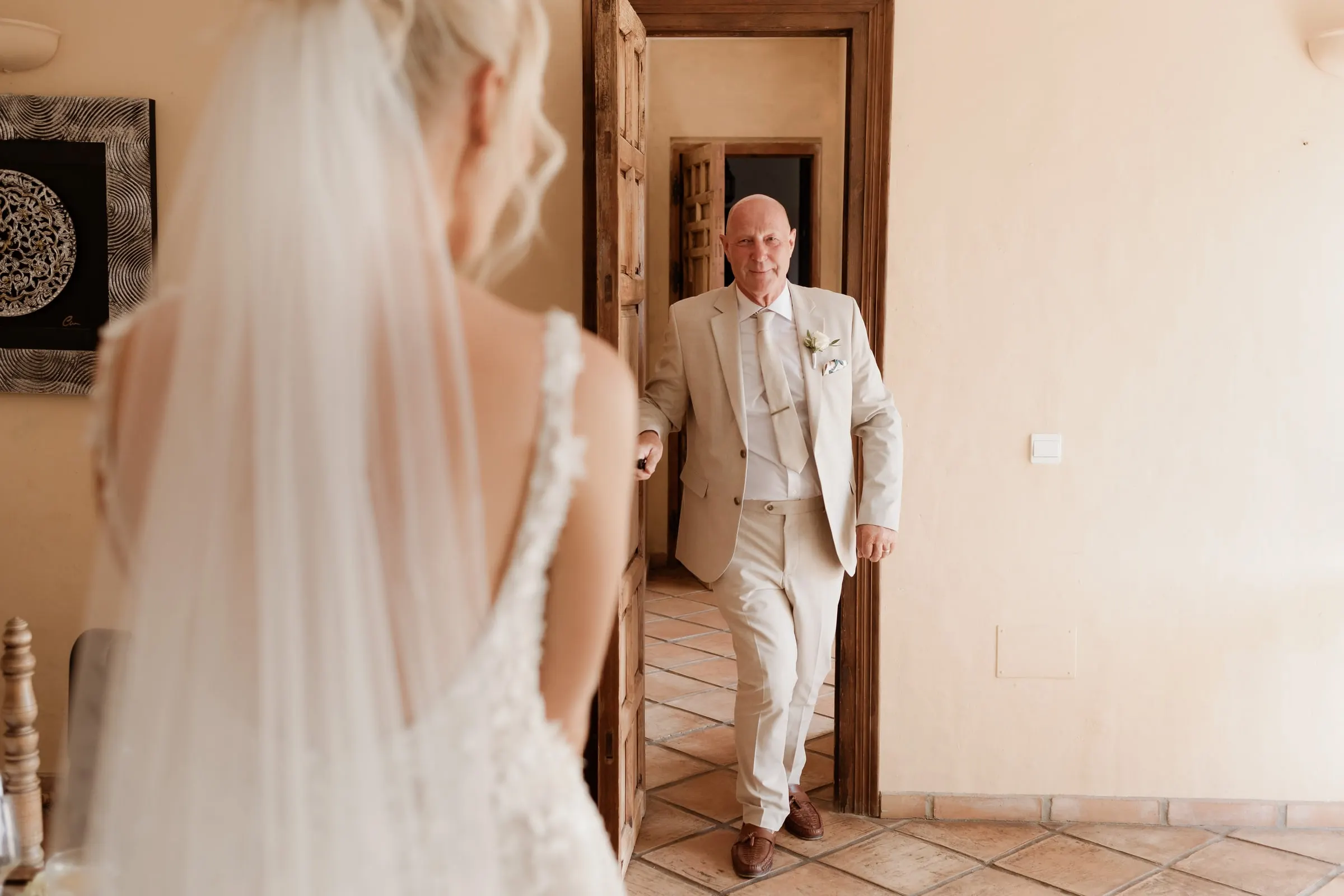 Father of the bride seeing her in her veil for the first time at the doorway