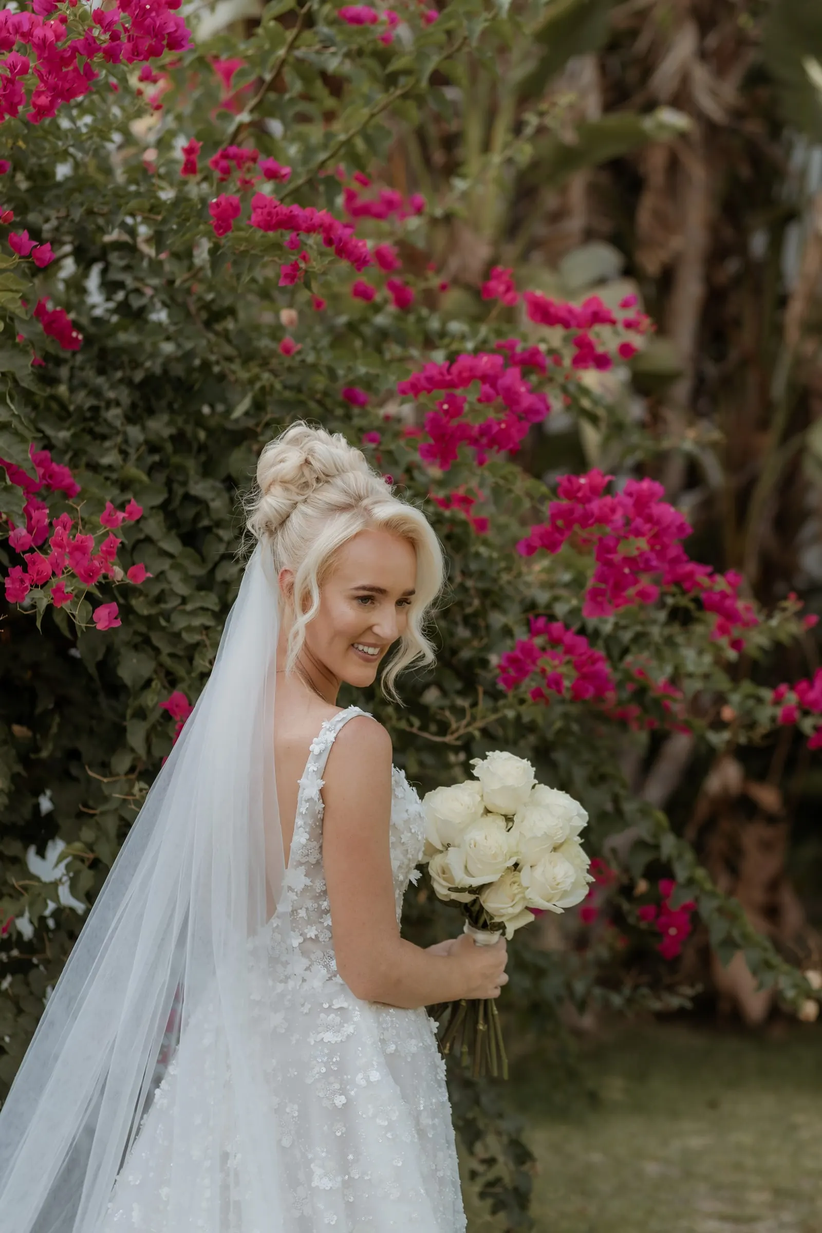 Bride with her bouquet in front of pink bougainvillea, Hacienda San José