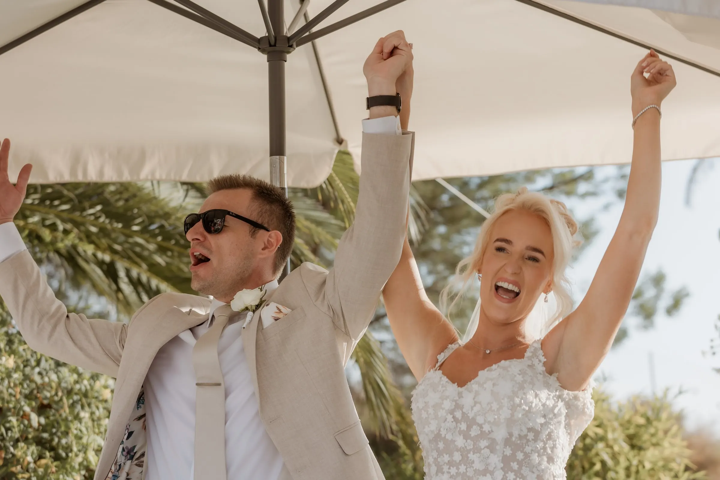 Bride and groom raising their arms as they enter the reception in Mijas