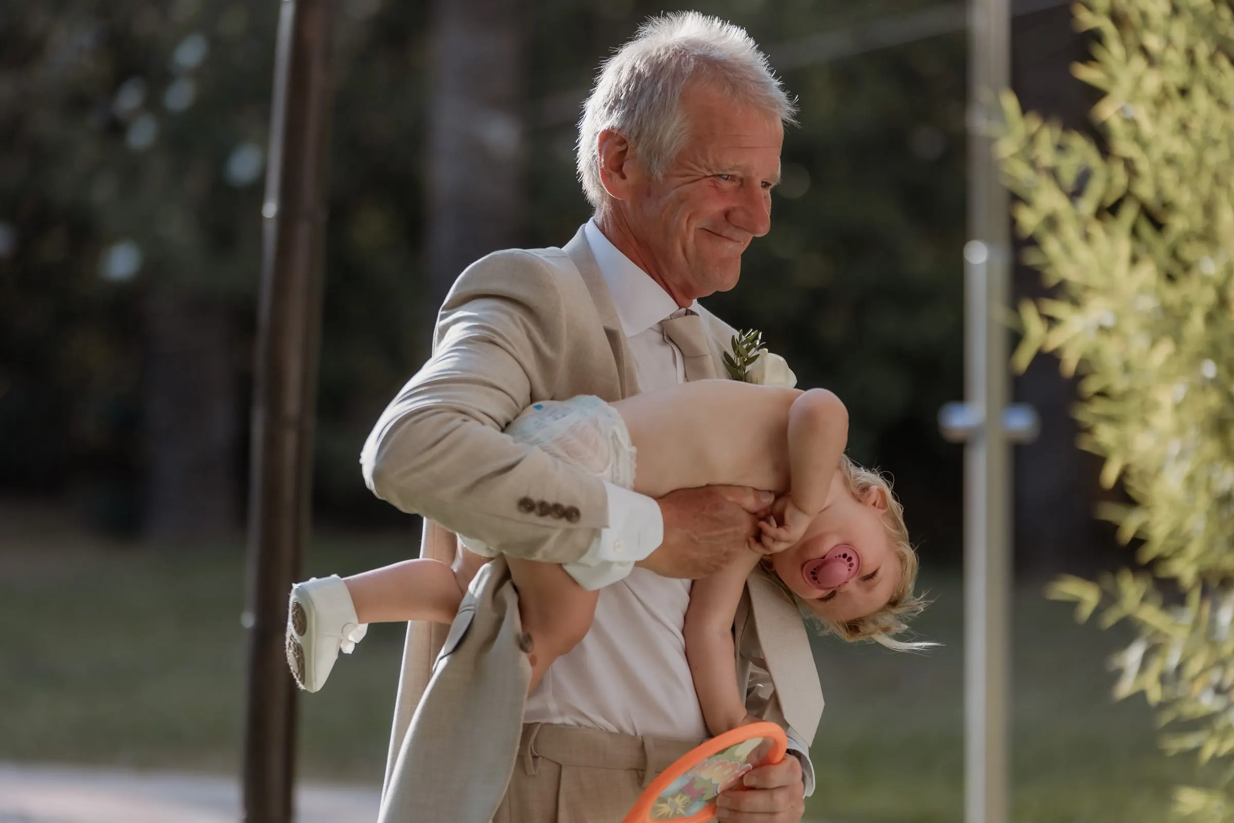 Grandfather lifting a giggling toddler in the garden at Hacienda San José