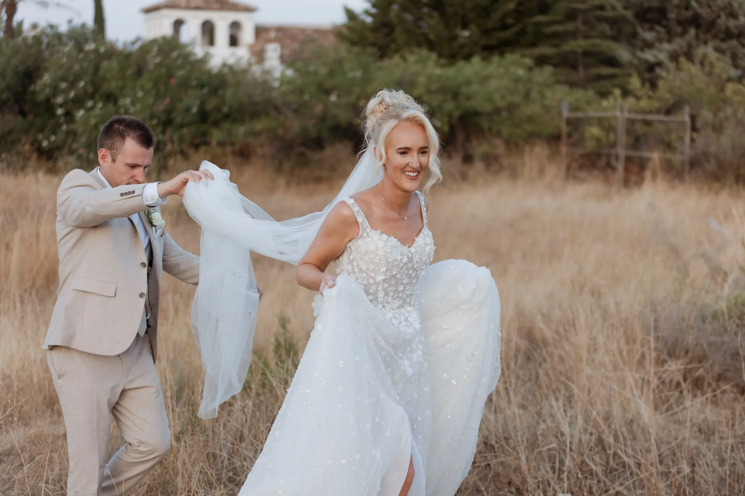 Groom lifting the bride's veil in the wind in a dry meadow, Mijas