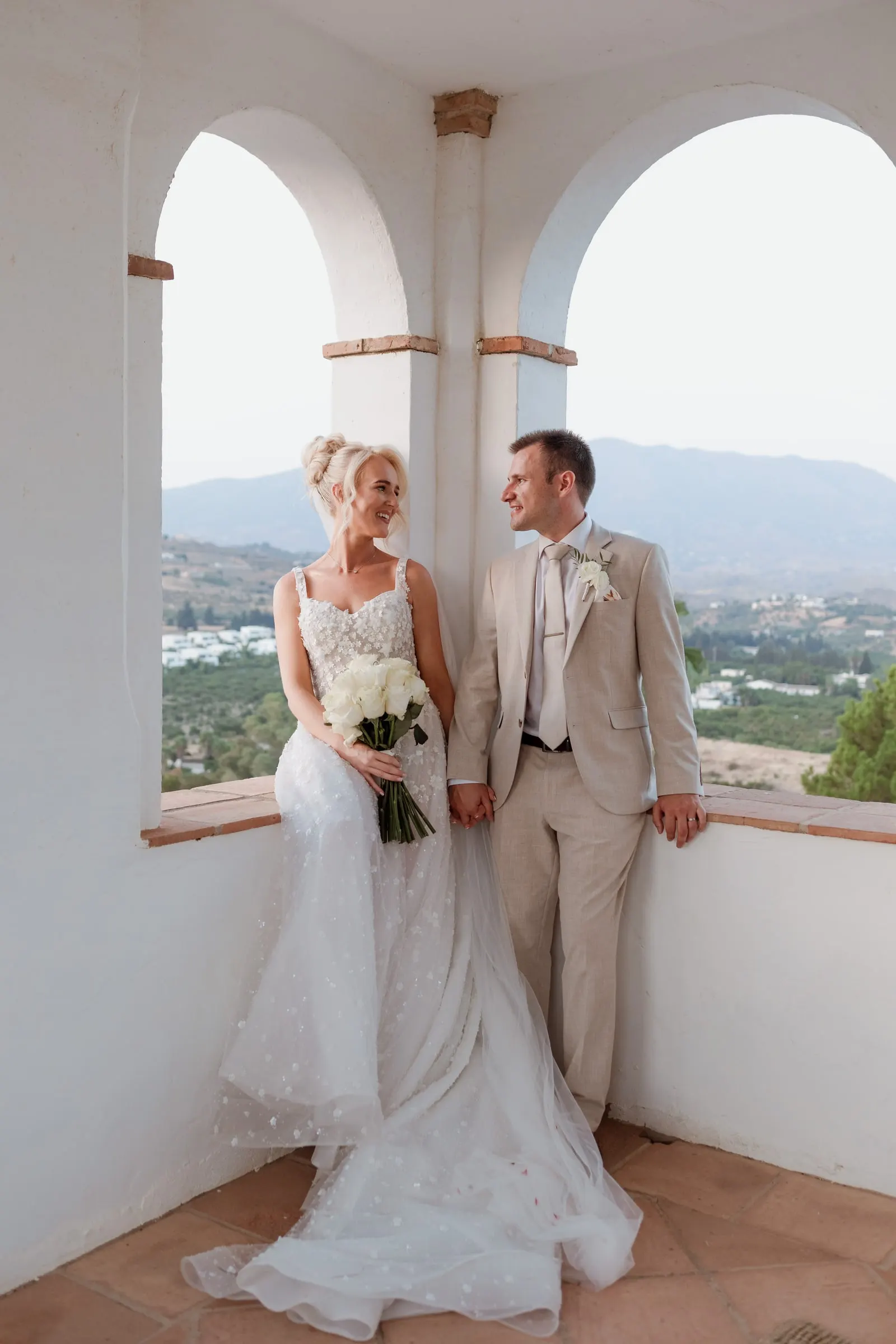 Full-length portrait of the couple in the twin arches of the tower at Hacienda San José, Mijas