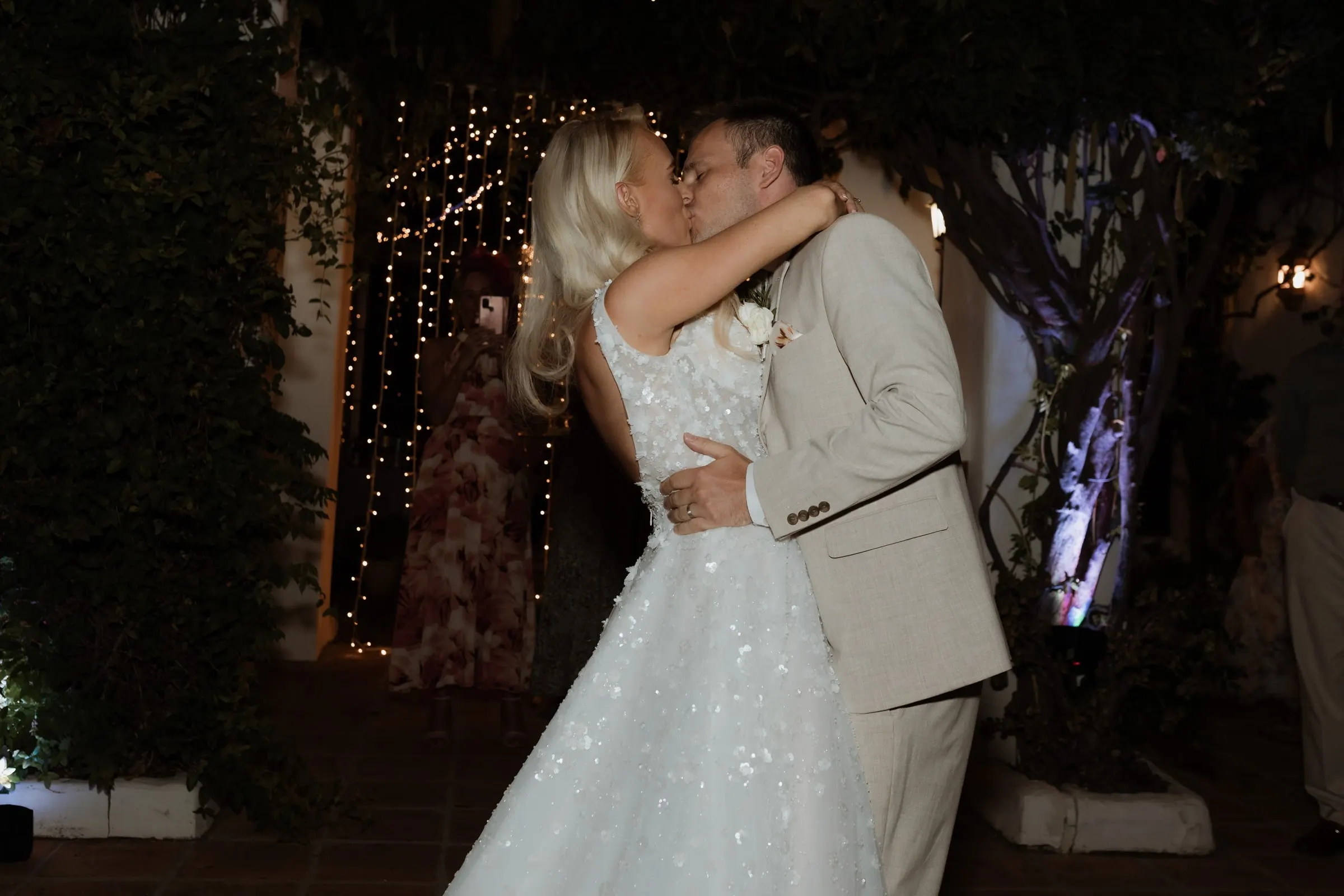 Newlyweds kissing on the dance floor under the fairy lights