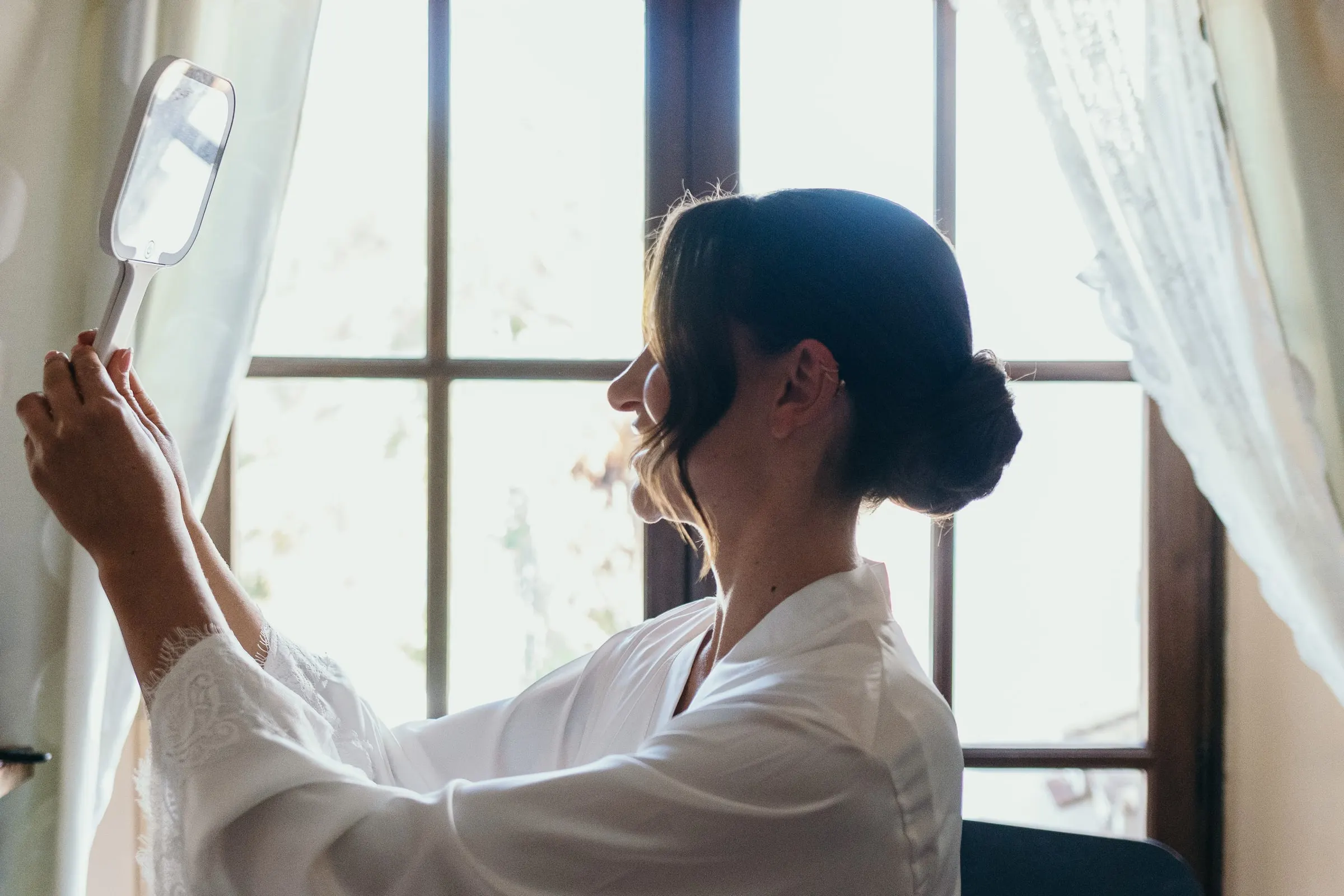 Bride getting ready by a bright window at Hacienda San José