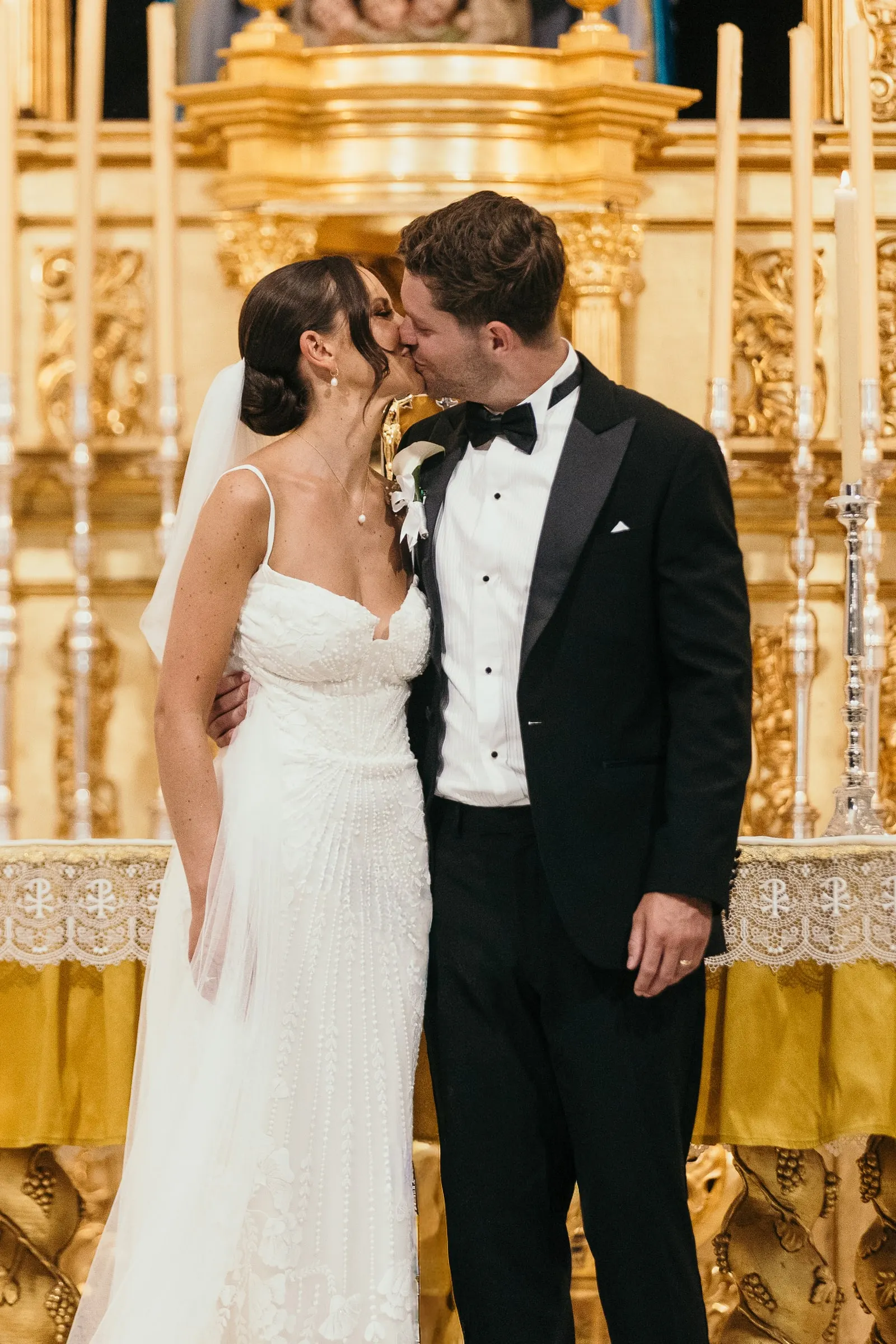 Couple kissing in front of the golden altarpiece, wedding in Mijas