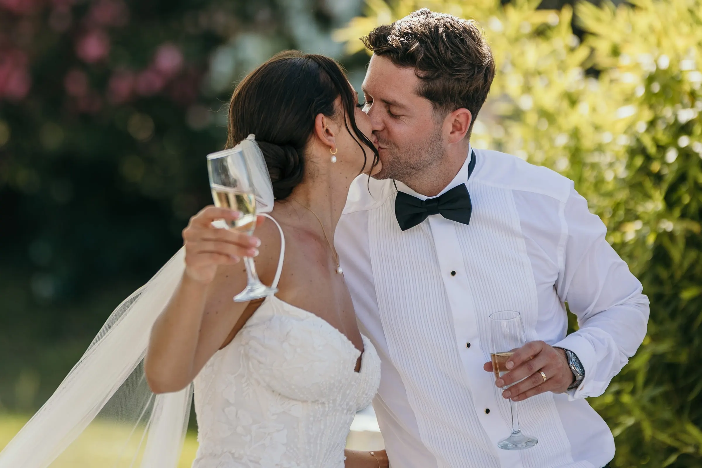 Bride and groom kissing as they raise their glasses