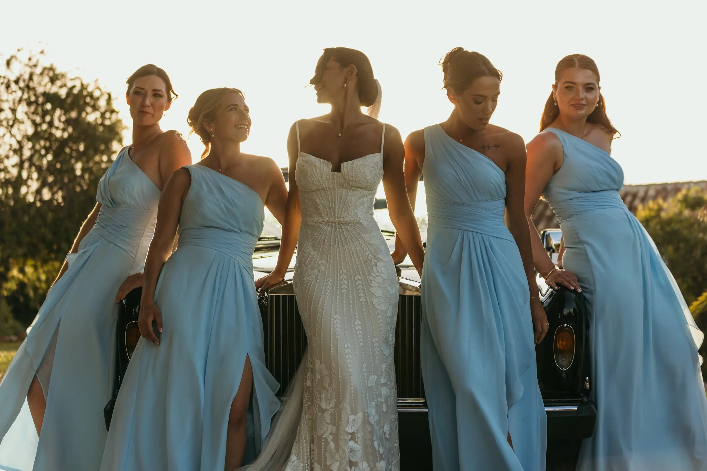 Bride laughing with her bridesmaids in pale blue dresses
