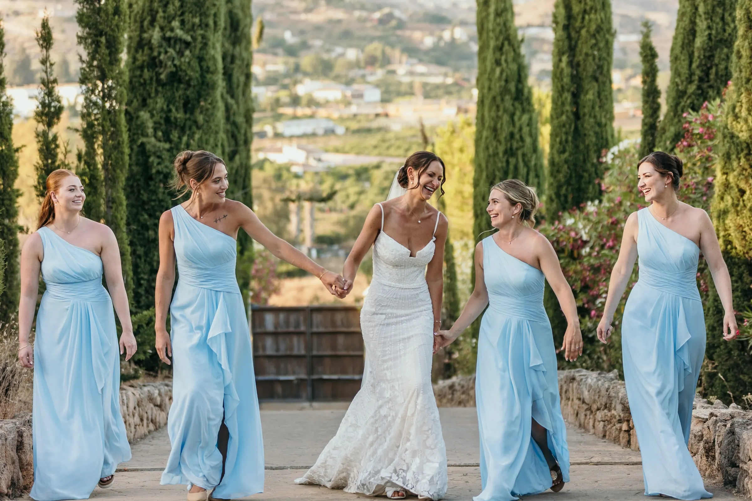 Bridesmaids dancing in a line between the cypress trees, Mijas
