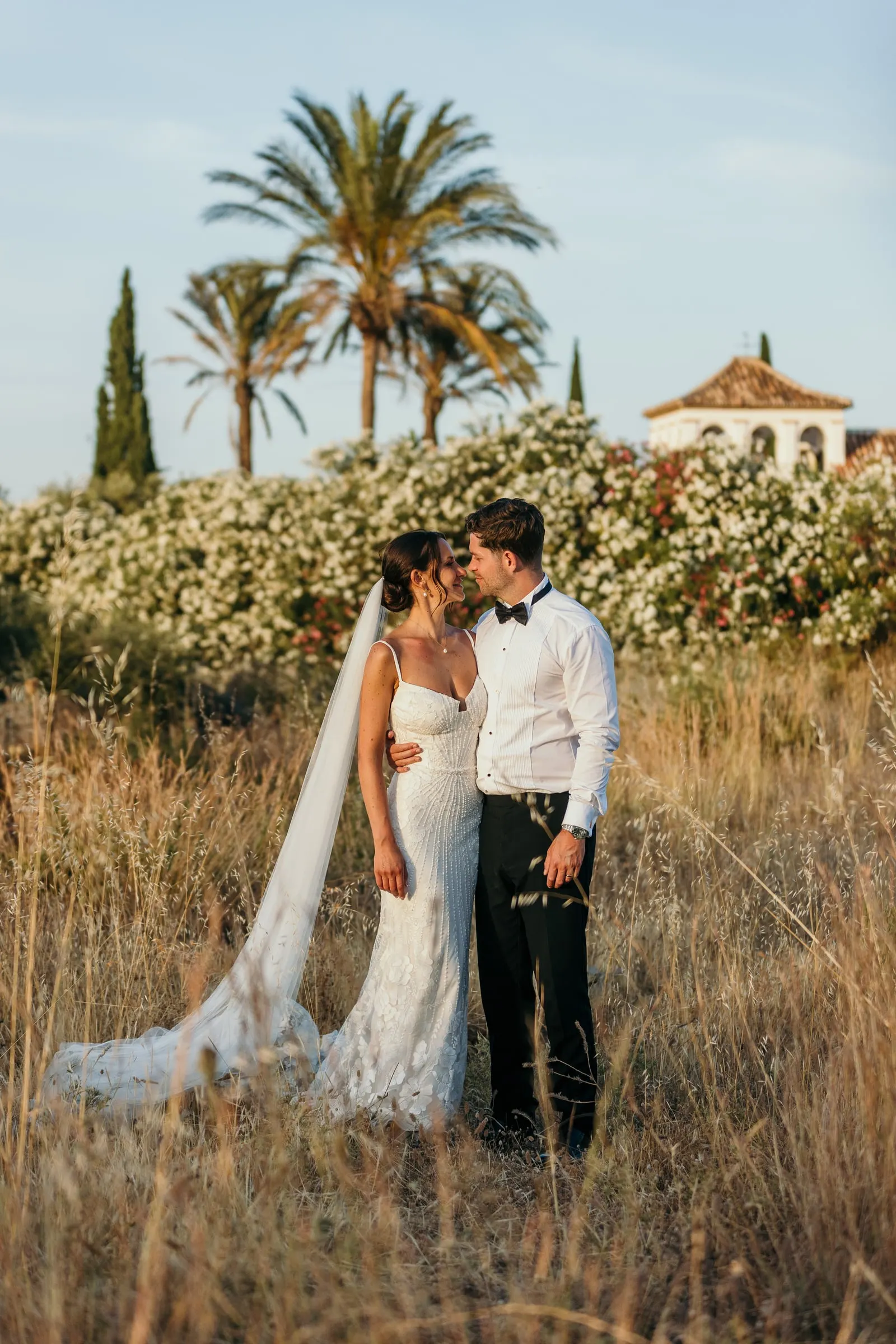Couple kissing in the tall grass with the hacienda tower behind