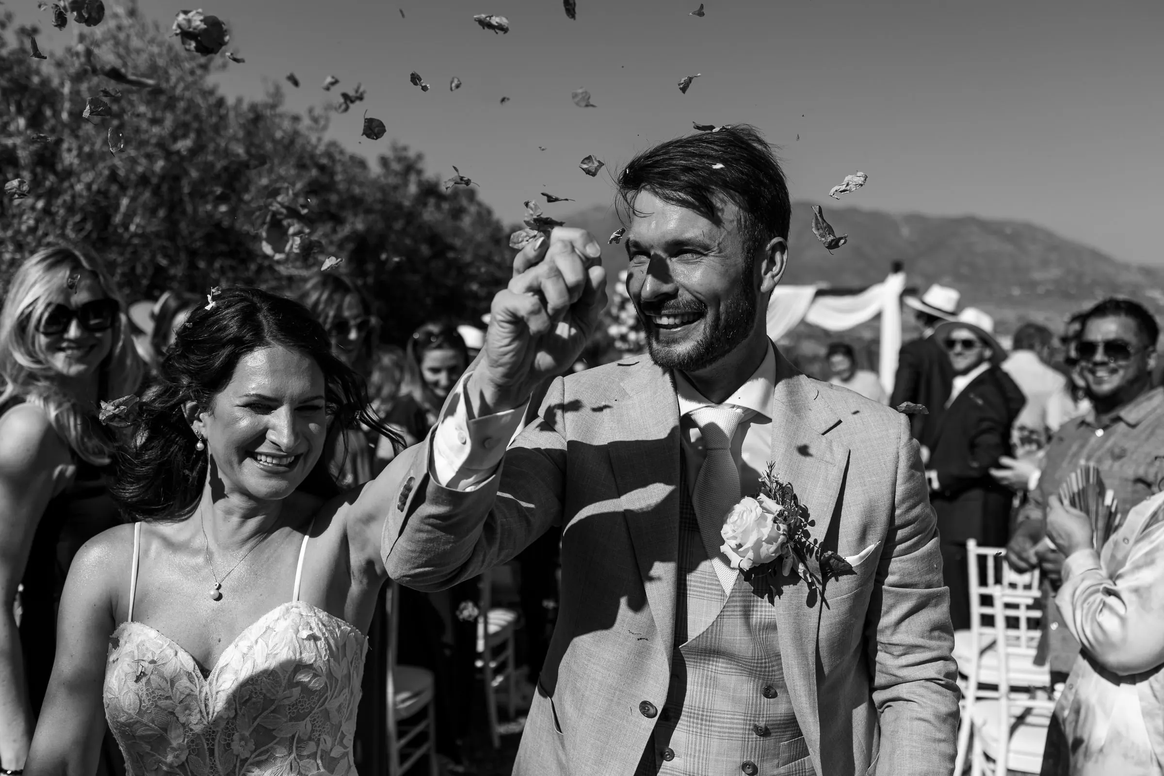 Black and white of the newlyweds laughing through a cloud of confetti after the ceremony, Hacienda San José, Mijas