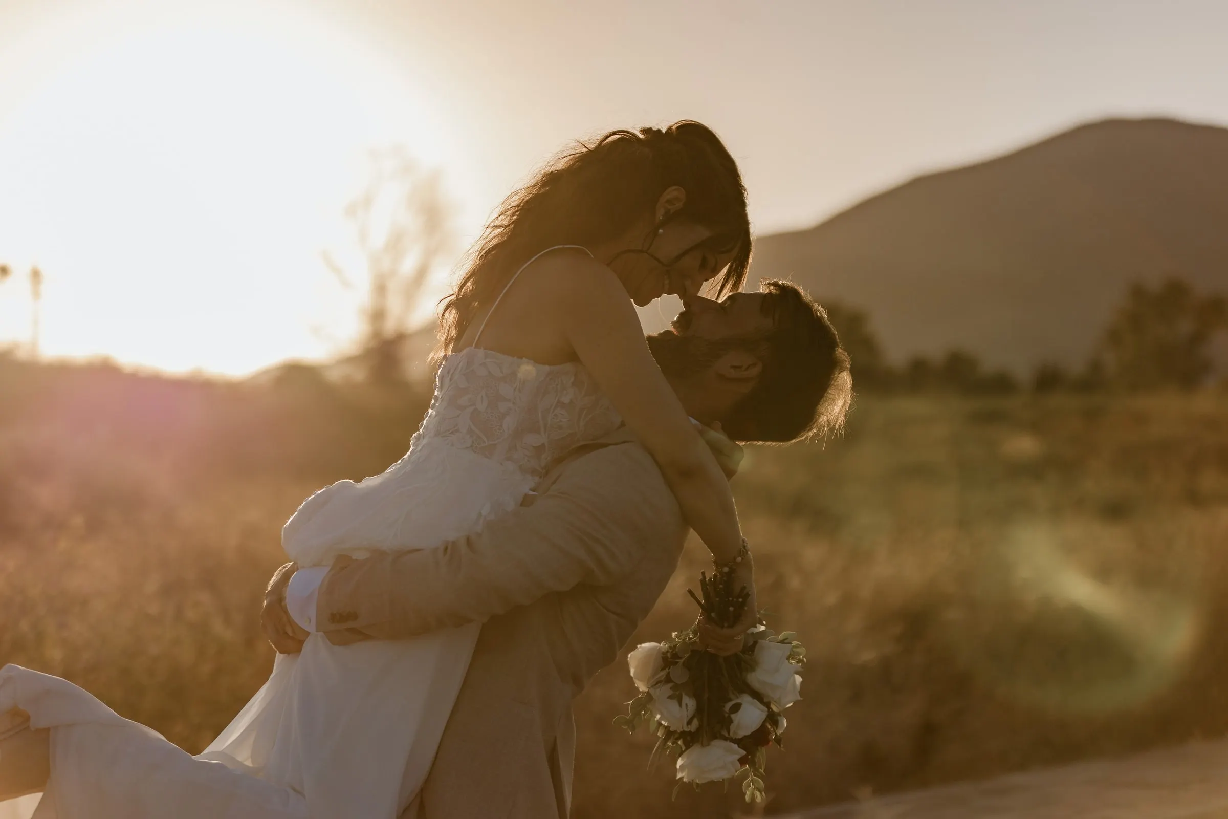 The groom lifting the bride in a kiss in a golden field at sunset, Hacienda San José, Mijas