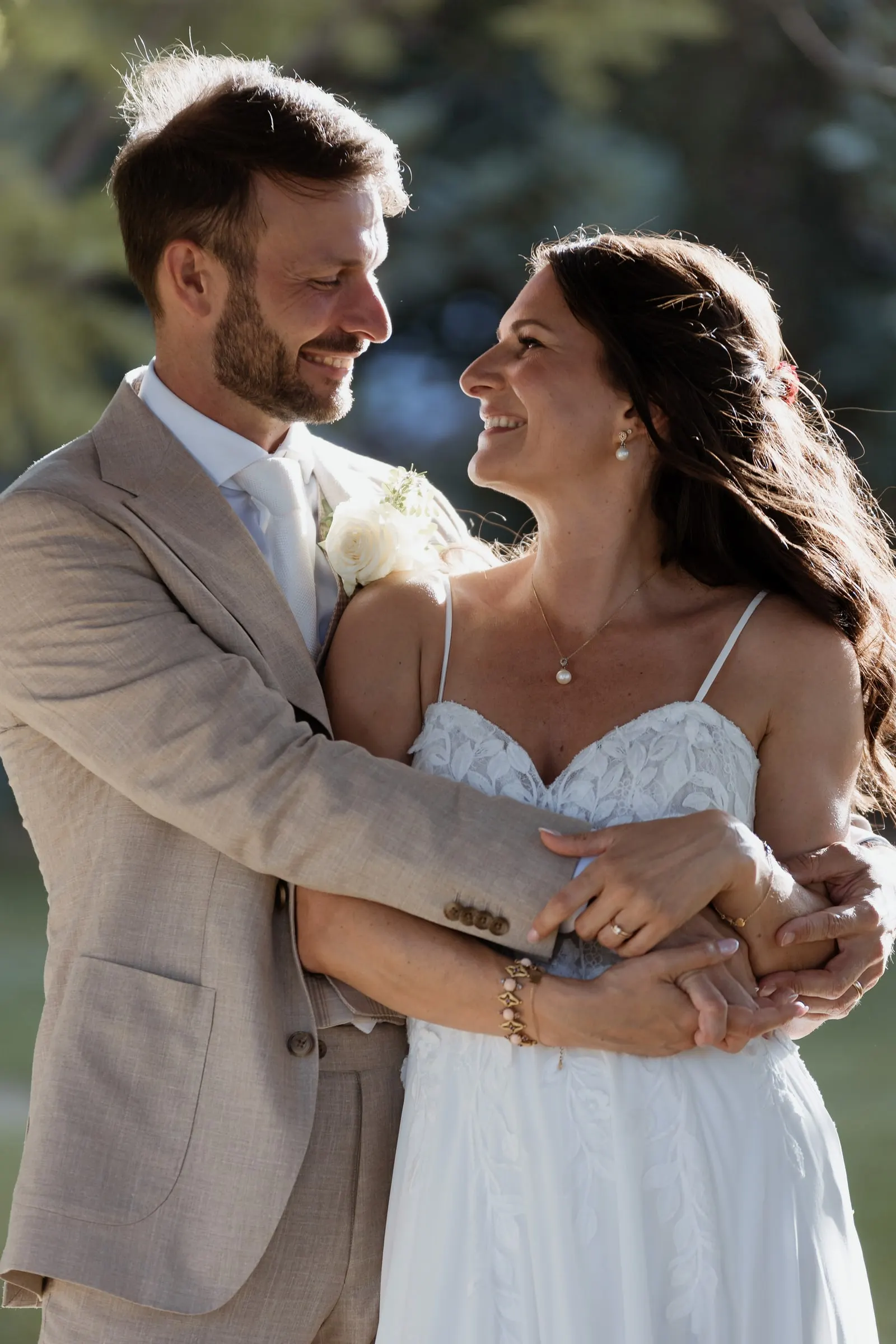 The groom holding the bride from behind as they smile at each other in warm light, Hacienda San José, Mijas