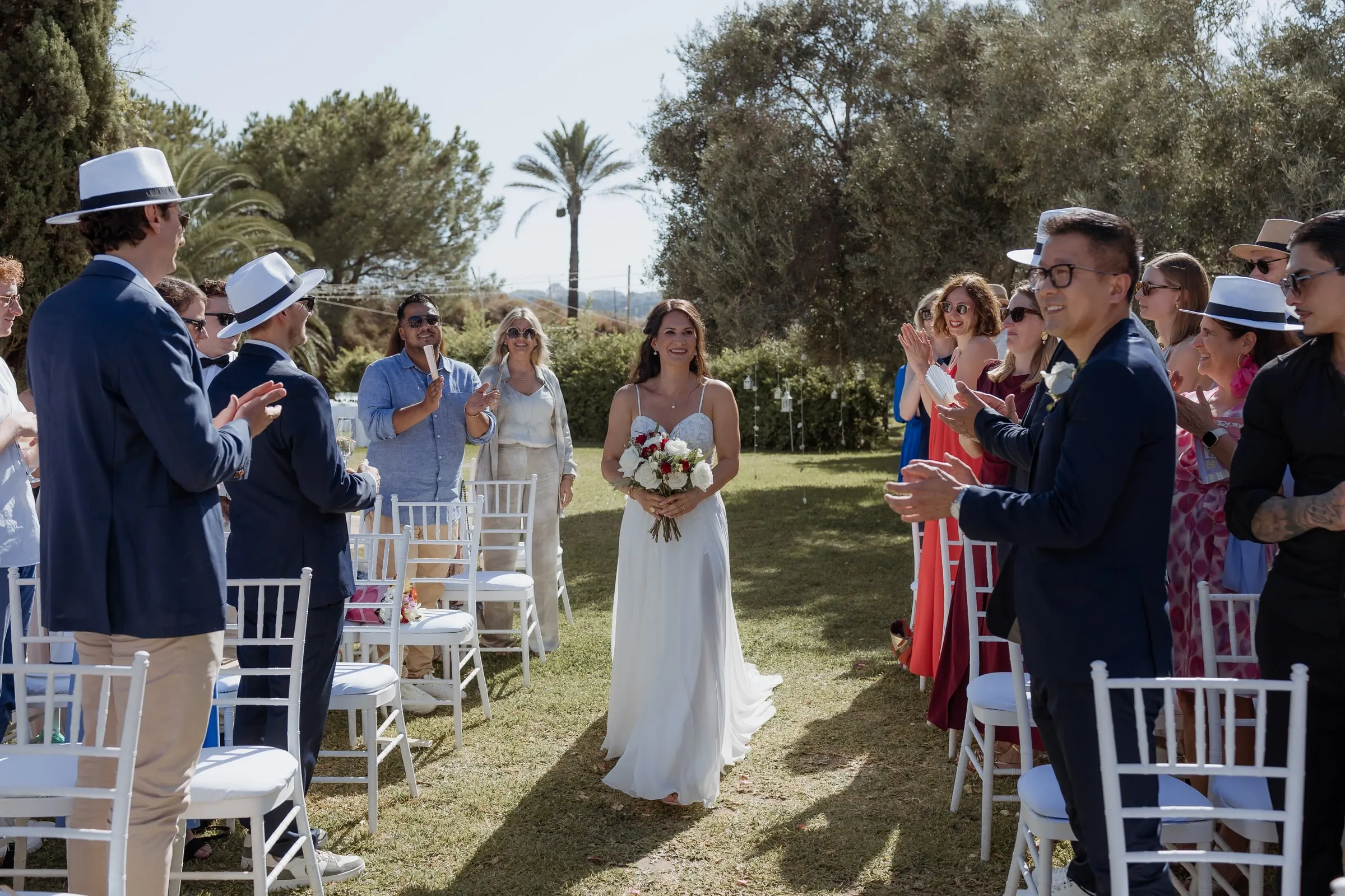 The bride walking alone down the aisle between rows of standing guests, Hacienda San José, Mijas