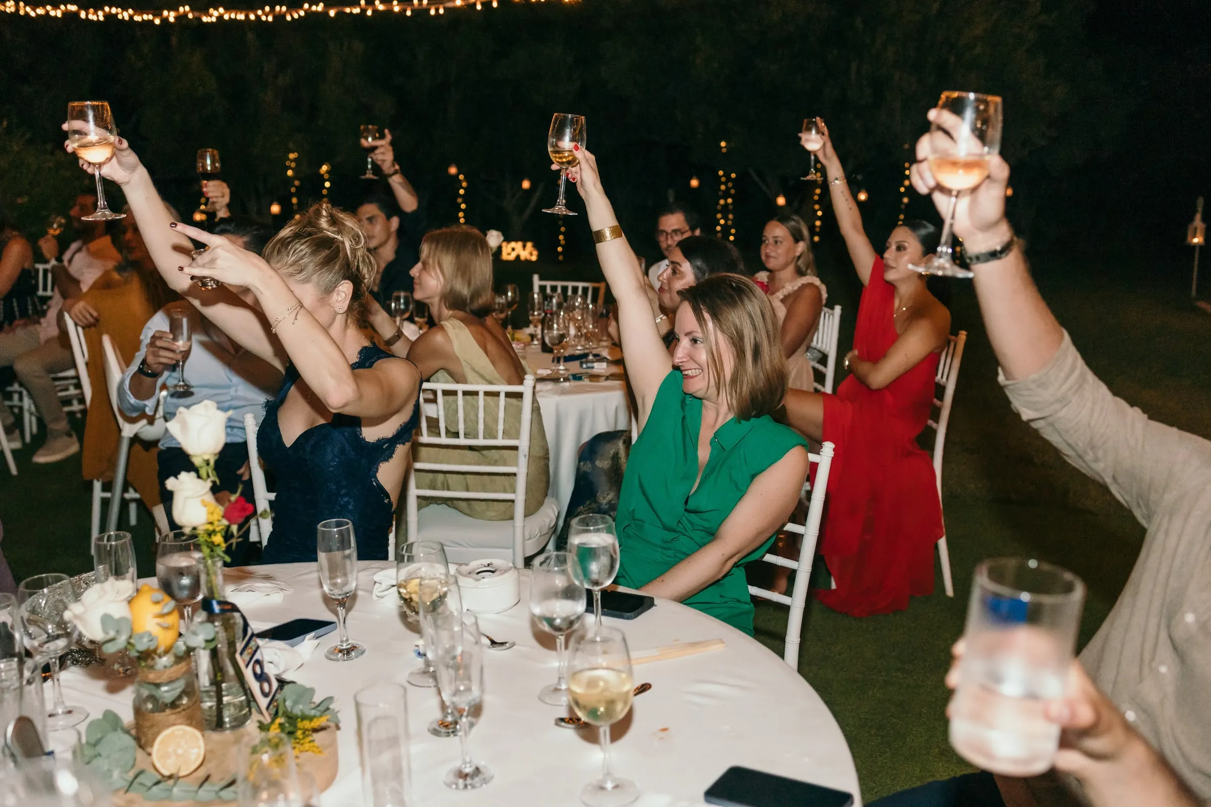 Guests at a round table raising their glasses high during the evening dinner, Hacienda San José, Mijas